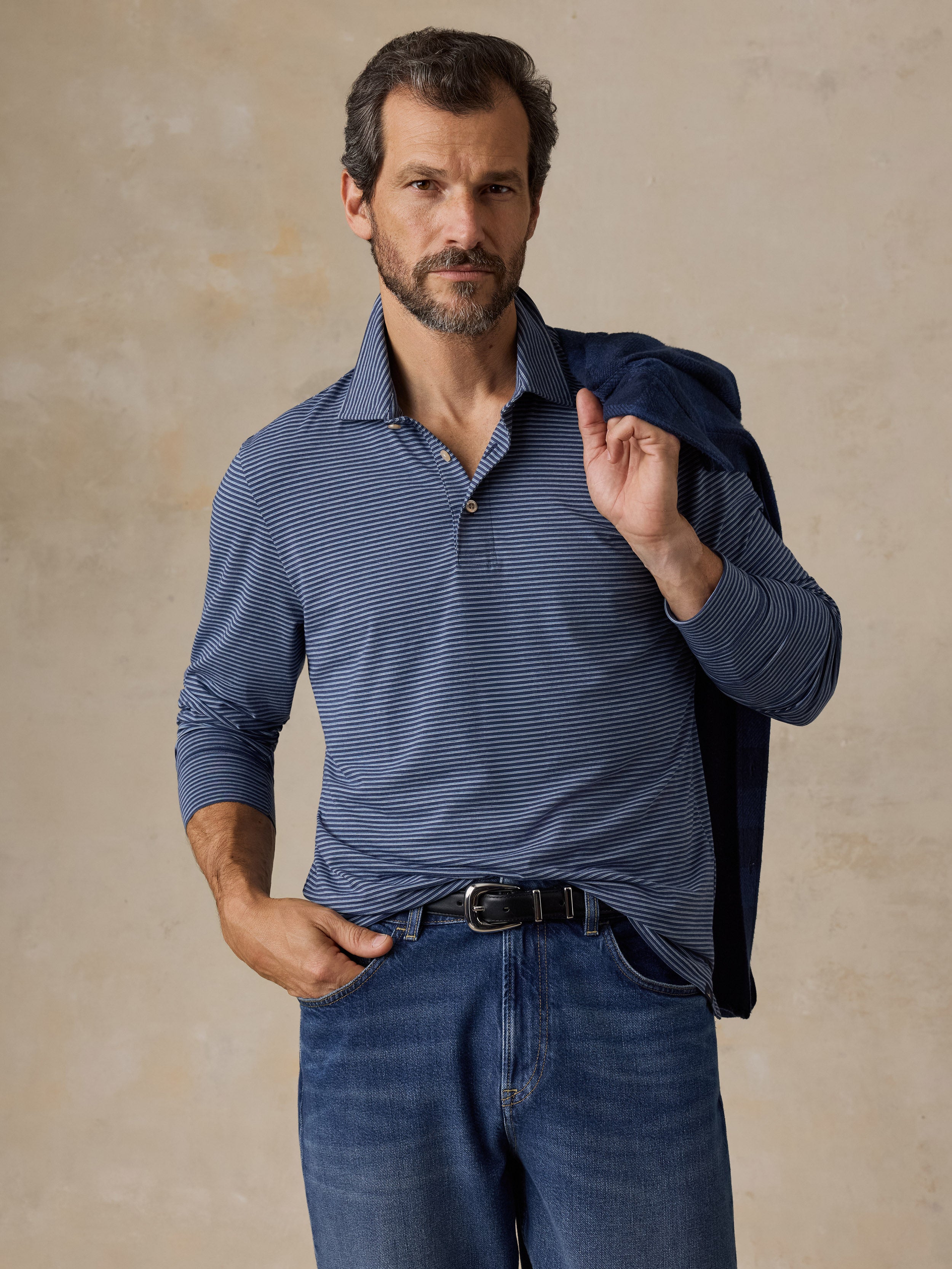 A man wearing a blue striped polo shirt and blue jeans