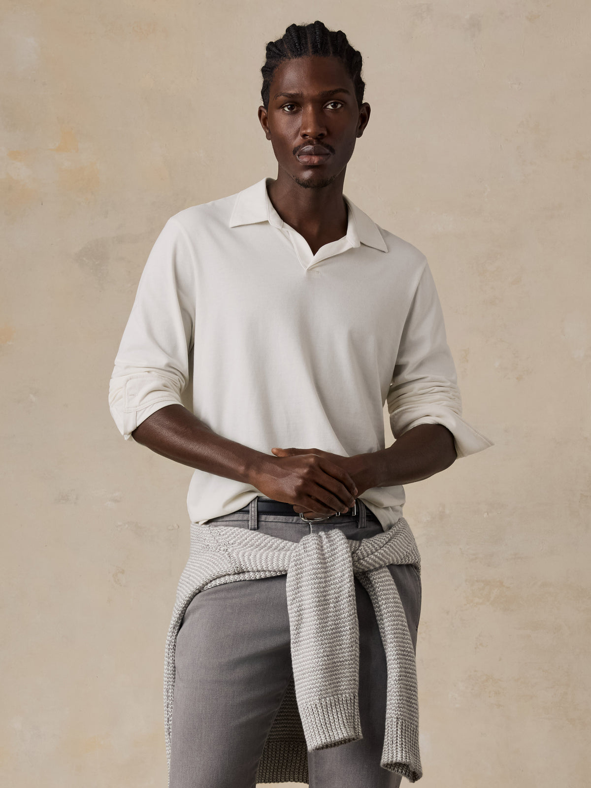 A man wearing a white long sleeve polo and grey pants, image 2 of 6