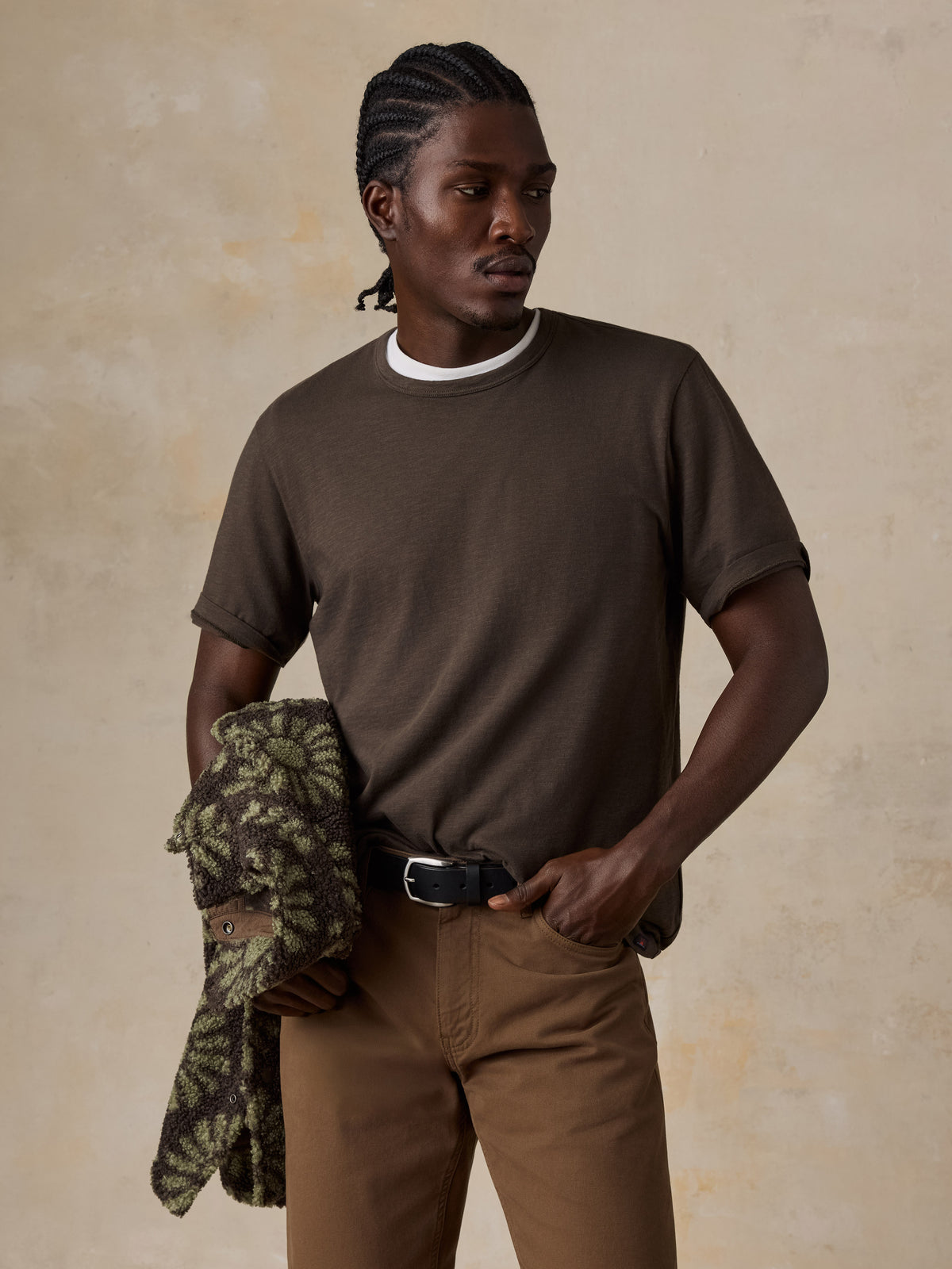 A man wearing a brown t-shirt and brown pants, image 1 of 6