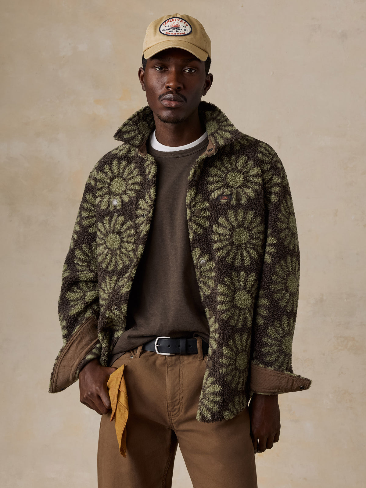A man wearing a floral fleece jacket over a brown tee and brown pants, image 7 of 7