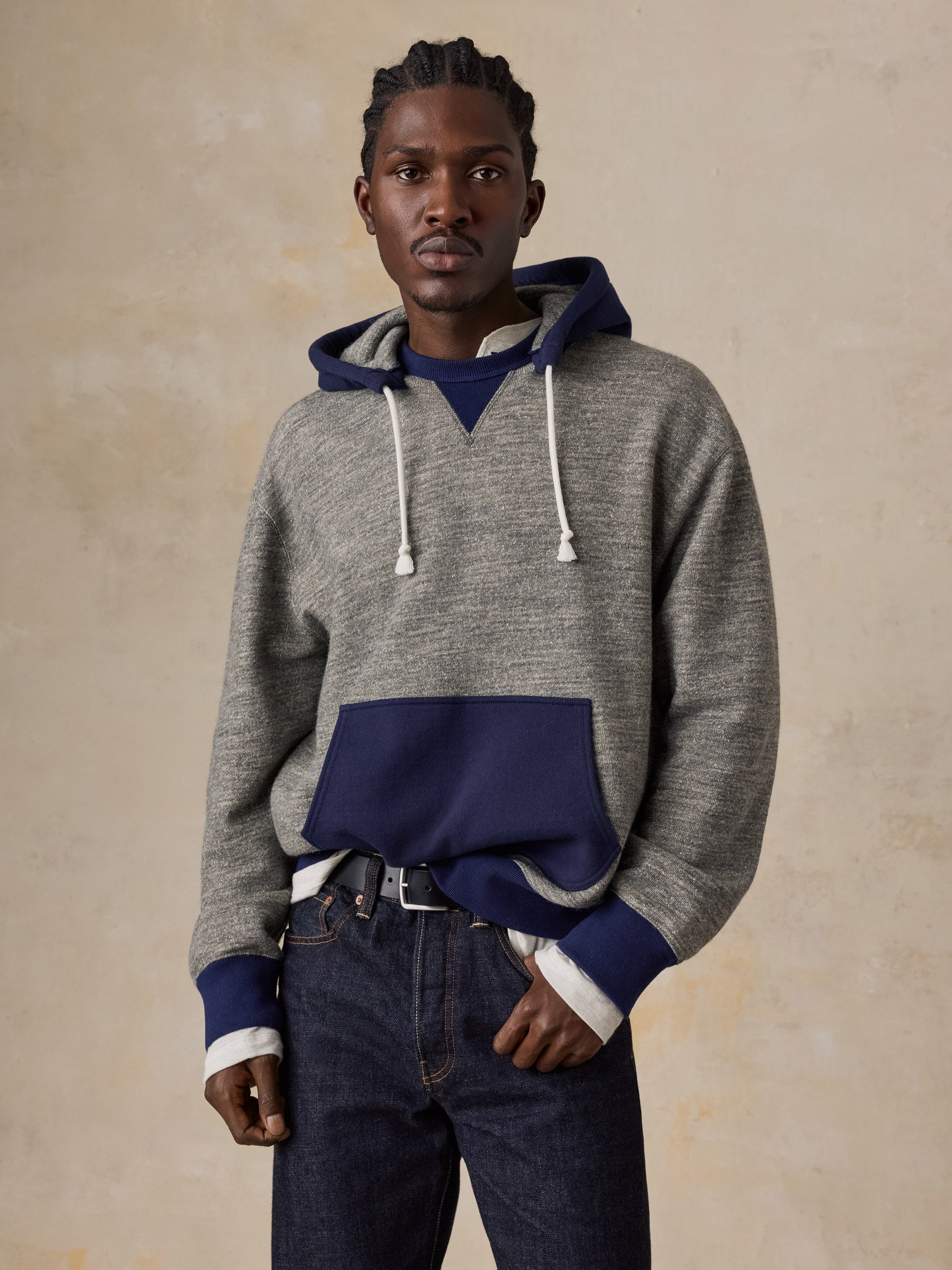 A man wearing a blue and grey hoodie with blue jeans