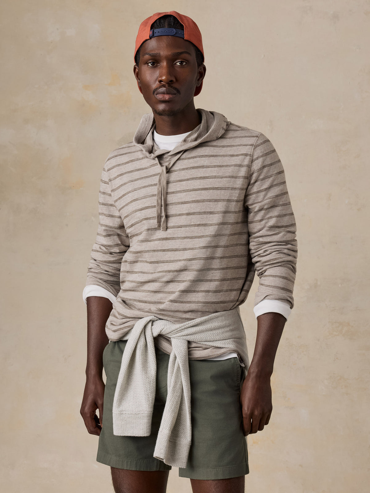 A man wearing a striped sweatshirt and green shorts, image 1 of 5
