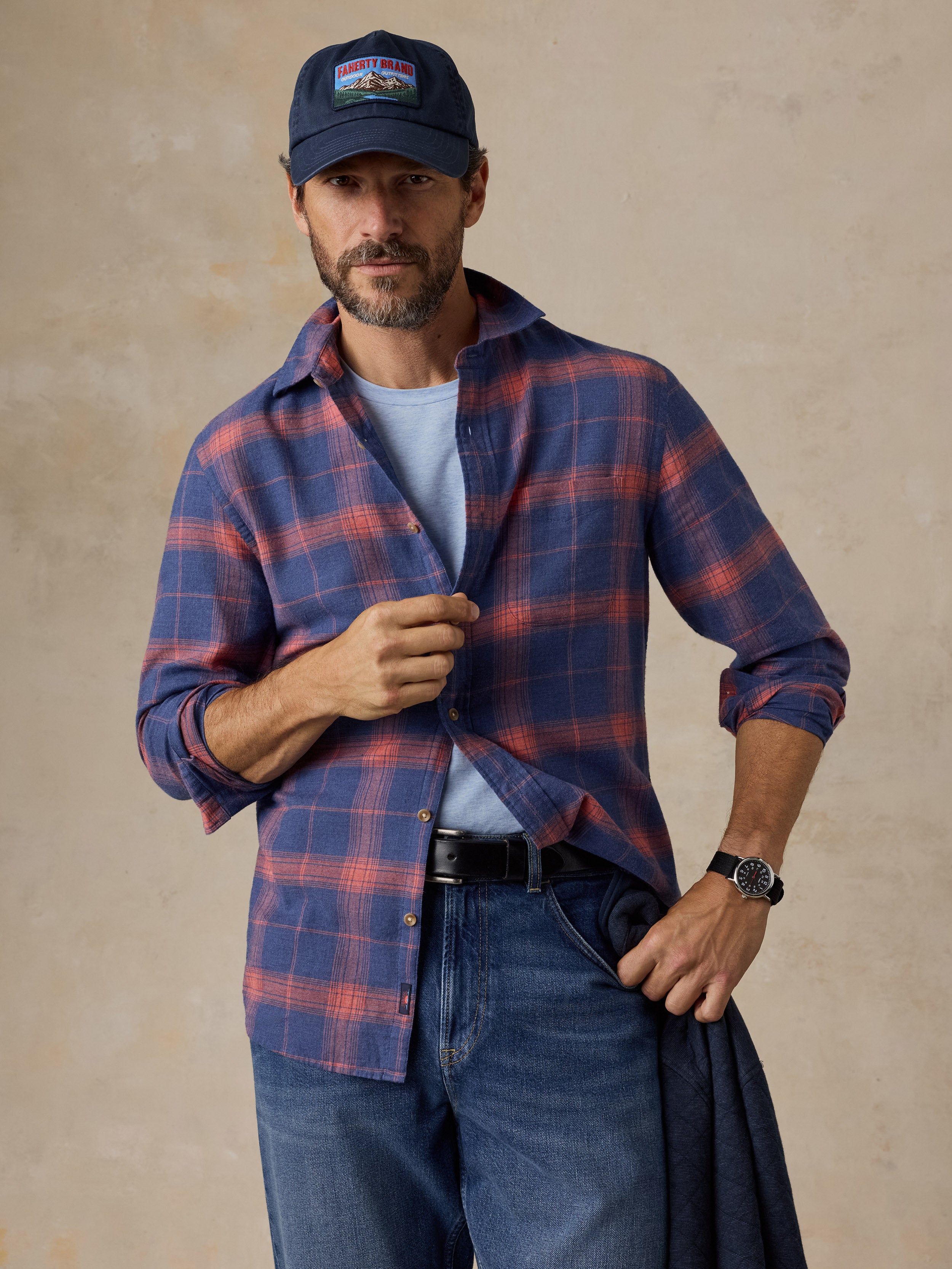 A man wearing a blue plaid shirt, blue jeans, and a hat