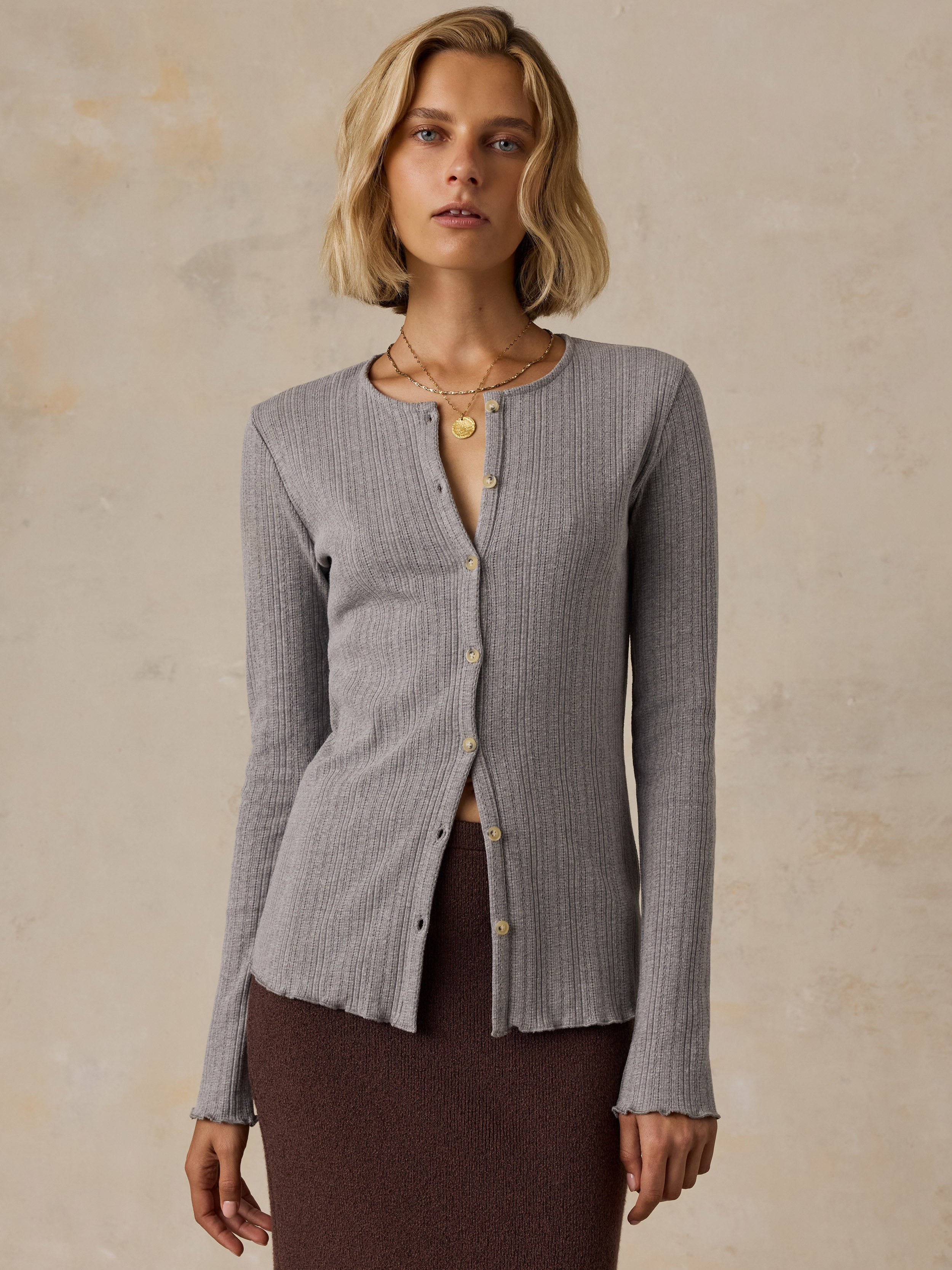 A woman wearing a grey cardigan and brown skirt