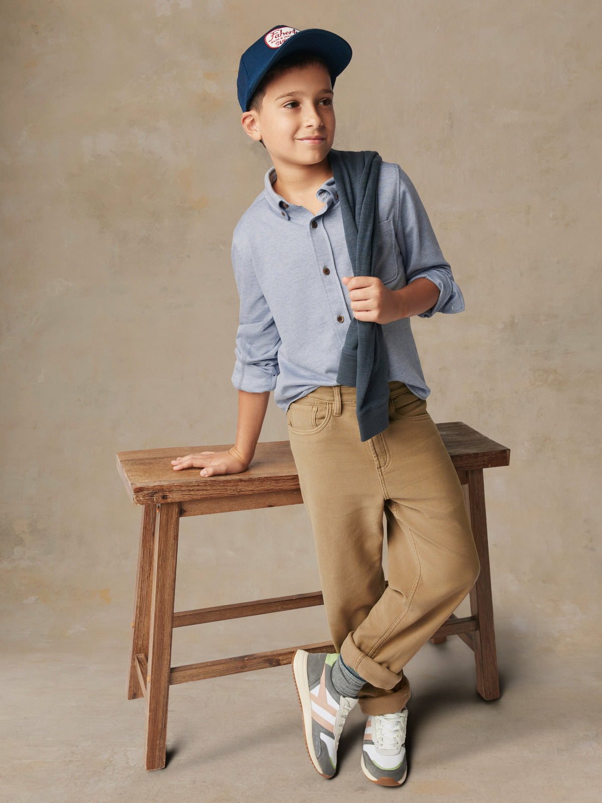 A child wearing a blue button up shirt and beige pants, image 1 of 7