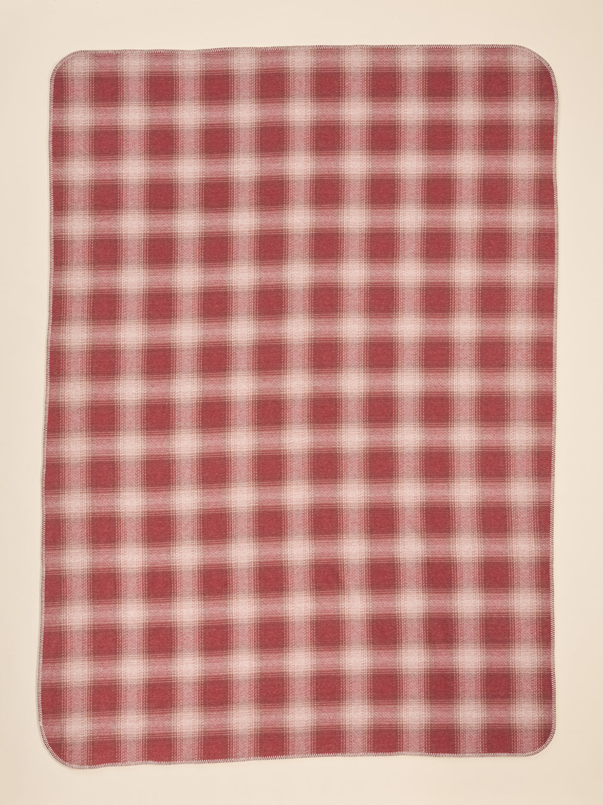 A rectangular red and white plaid blanket with rounded corners, displayed flat against a light beige background., image 3 of 3