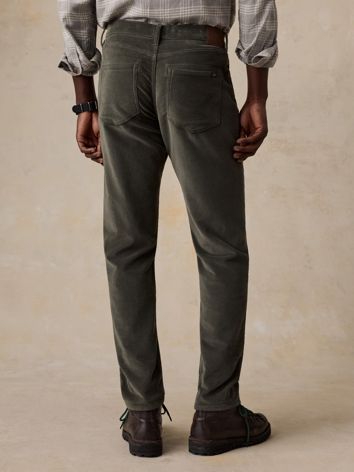 A man viewed from behind wearing green corduroy pants with a plaid button shirt, image 3 of 5