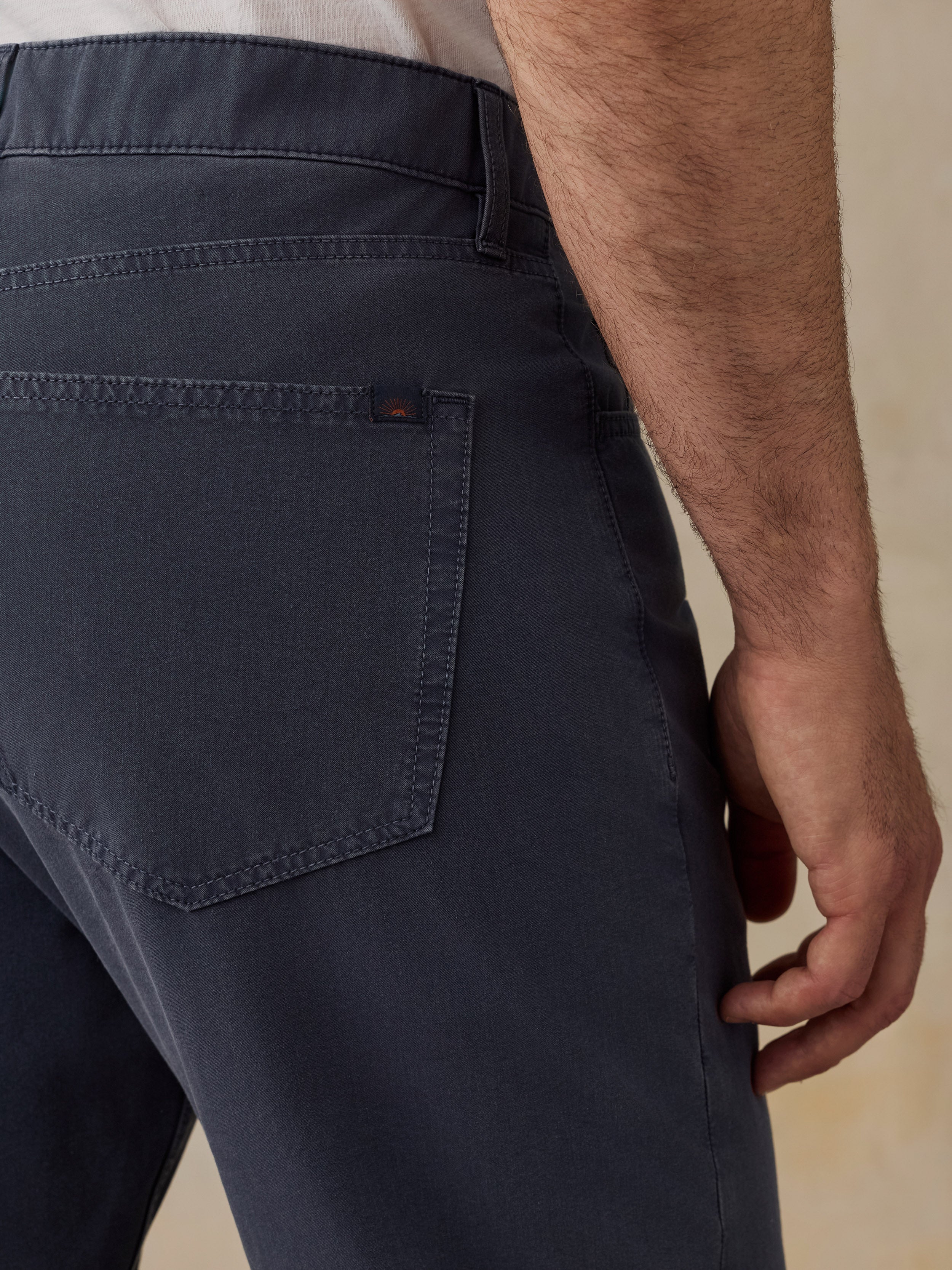 Close-up of a man wearing dark navy blue trousers, showing the back pocket and waistband area.