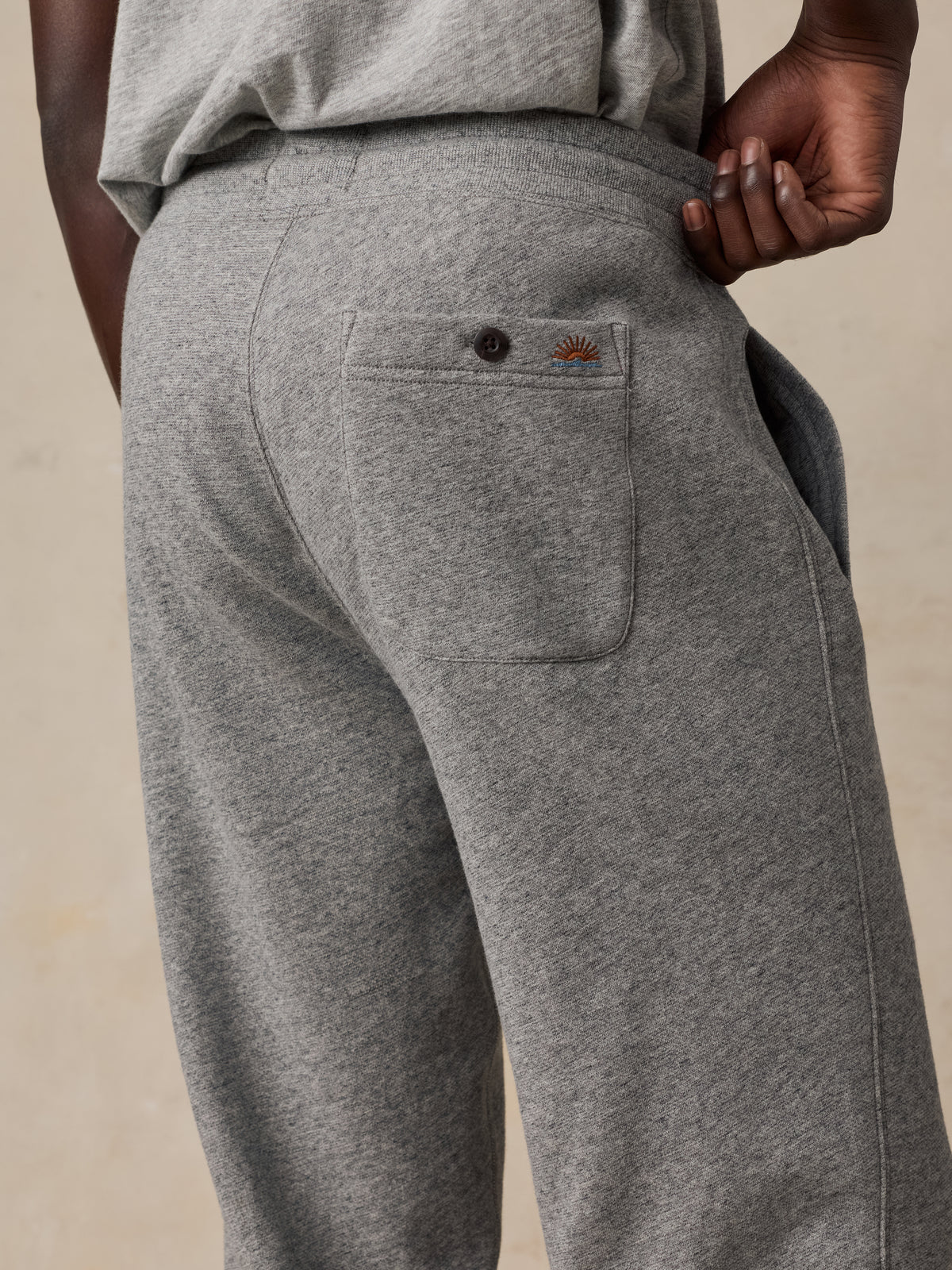 A man viewed from behind wearing a grey t-shirt and sweatpants, image 3 of 5