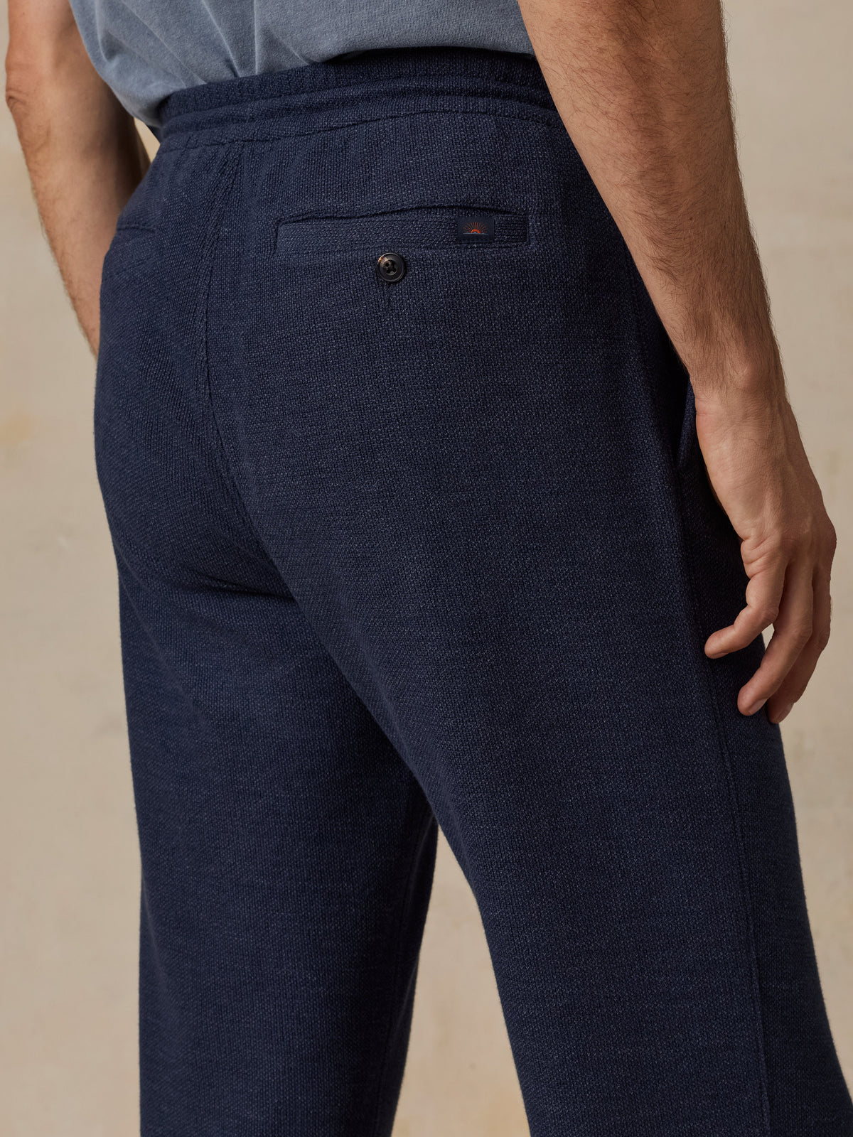 Close-up back view of a man wearing dark navy textured lounge pants with an elastic waistband and a small back pocket., image 6 of 6