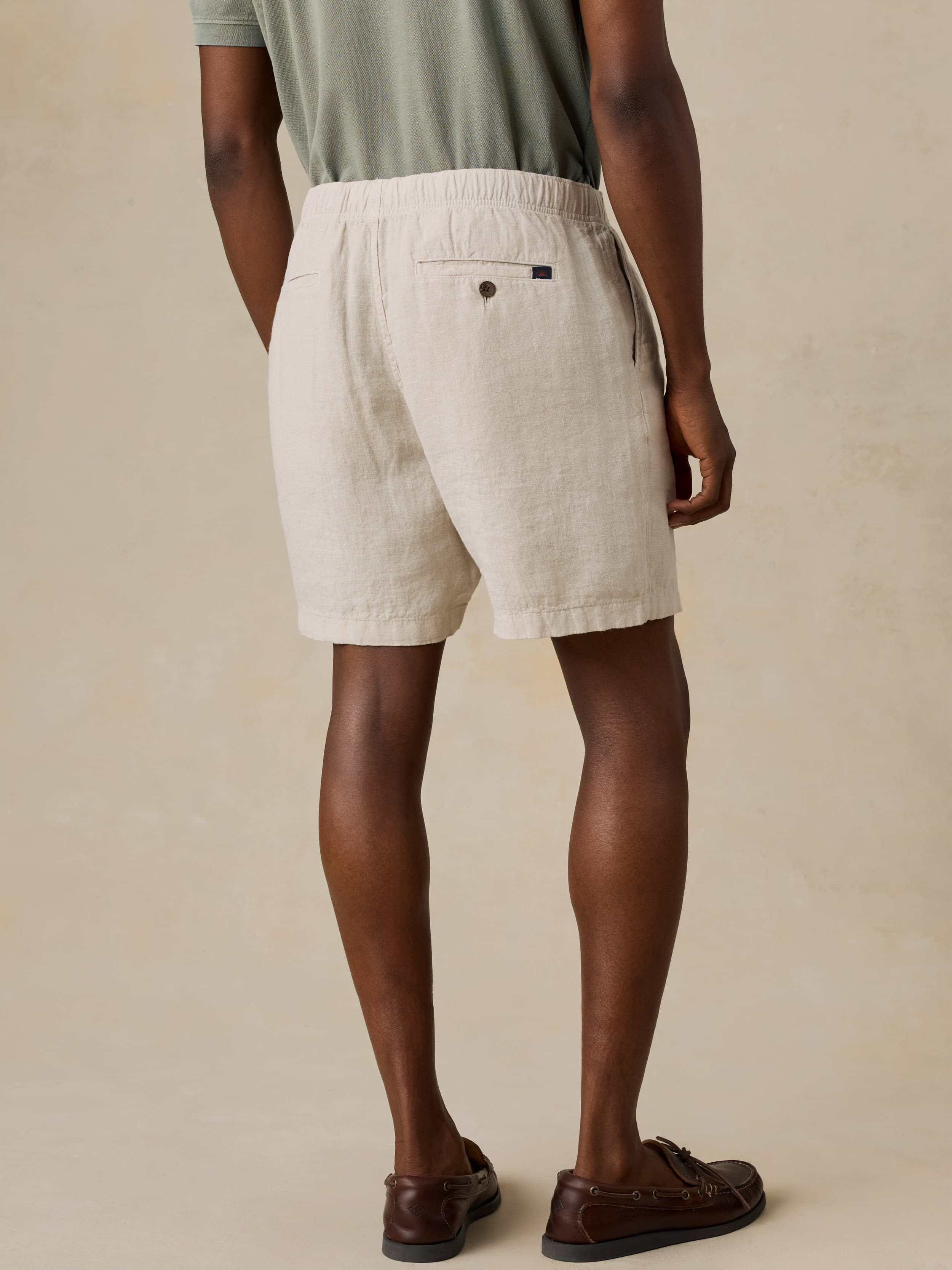 Man wearing beige linen shorts on a plain background