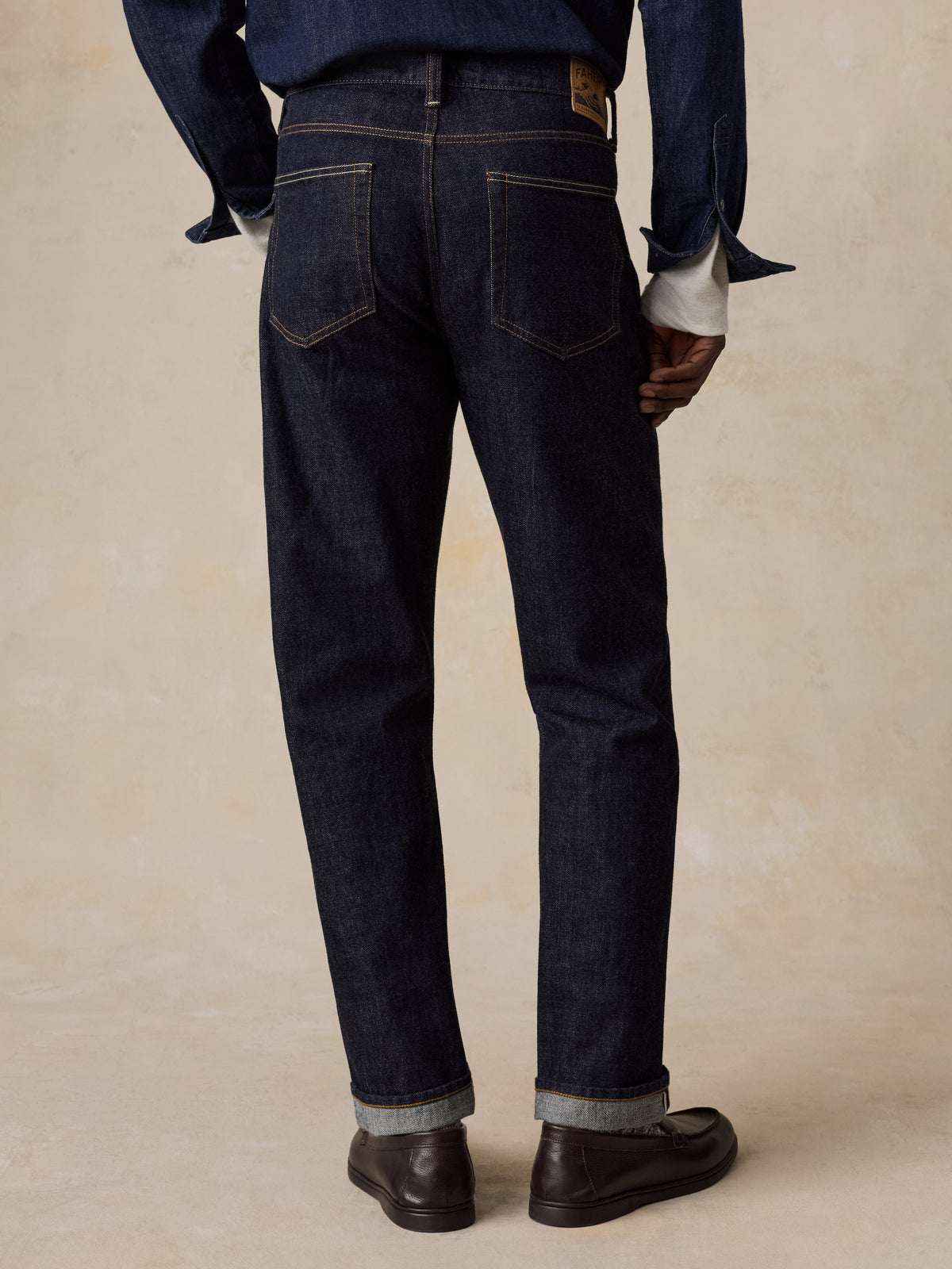 A man viewed from behind wearing blue selvedge denim pants and a blue denim shirt, image 4 of 6