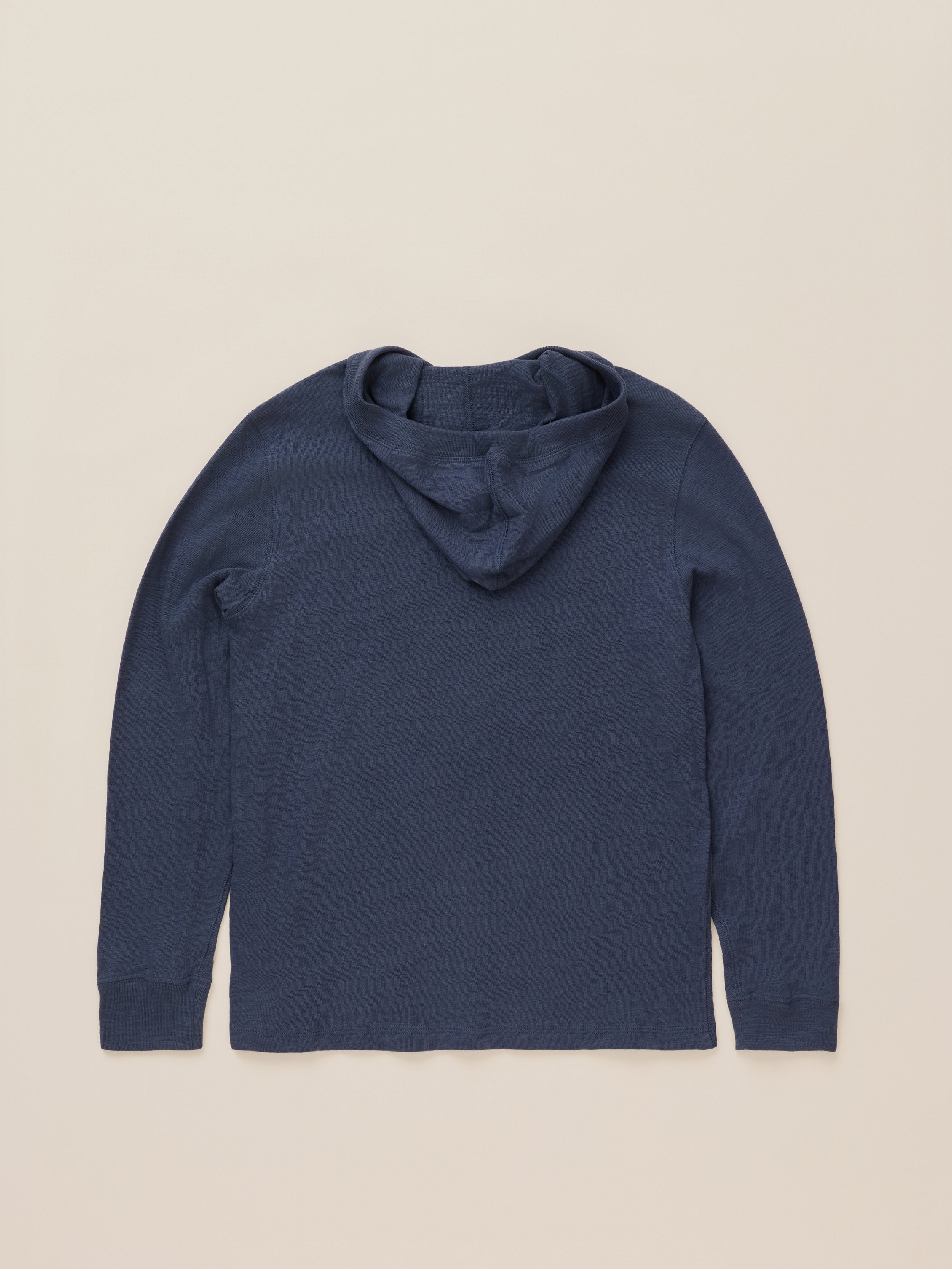 A dark navy blue long-sleeve hooded top laid flat against a light beige background.