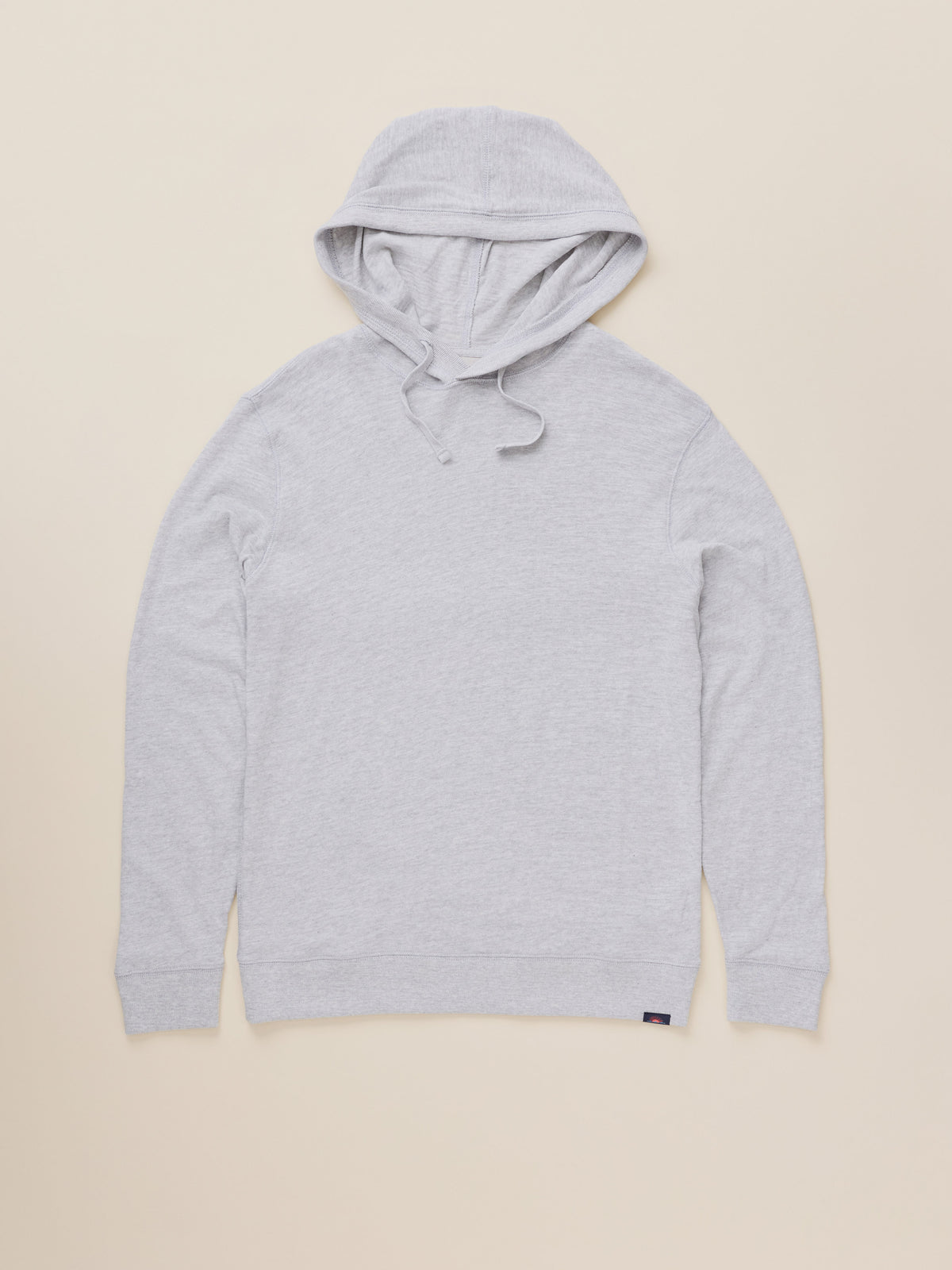 A light gray heather pullover hoodie with drawstrings, laid flat against a solid beige background., image 6 of 7
