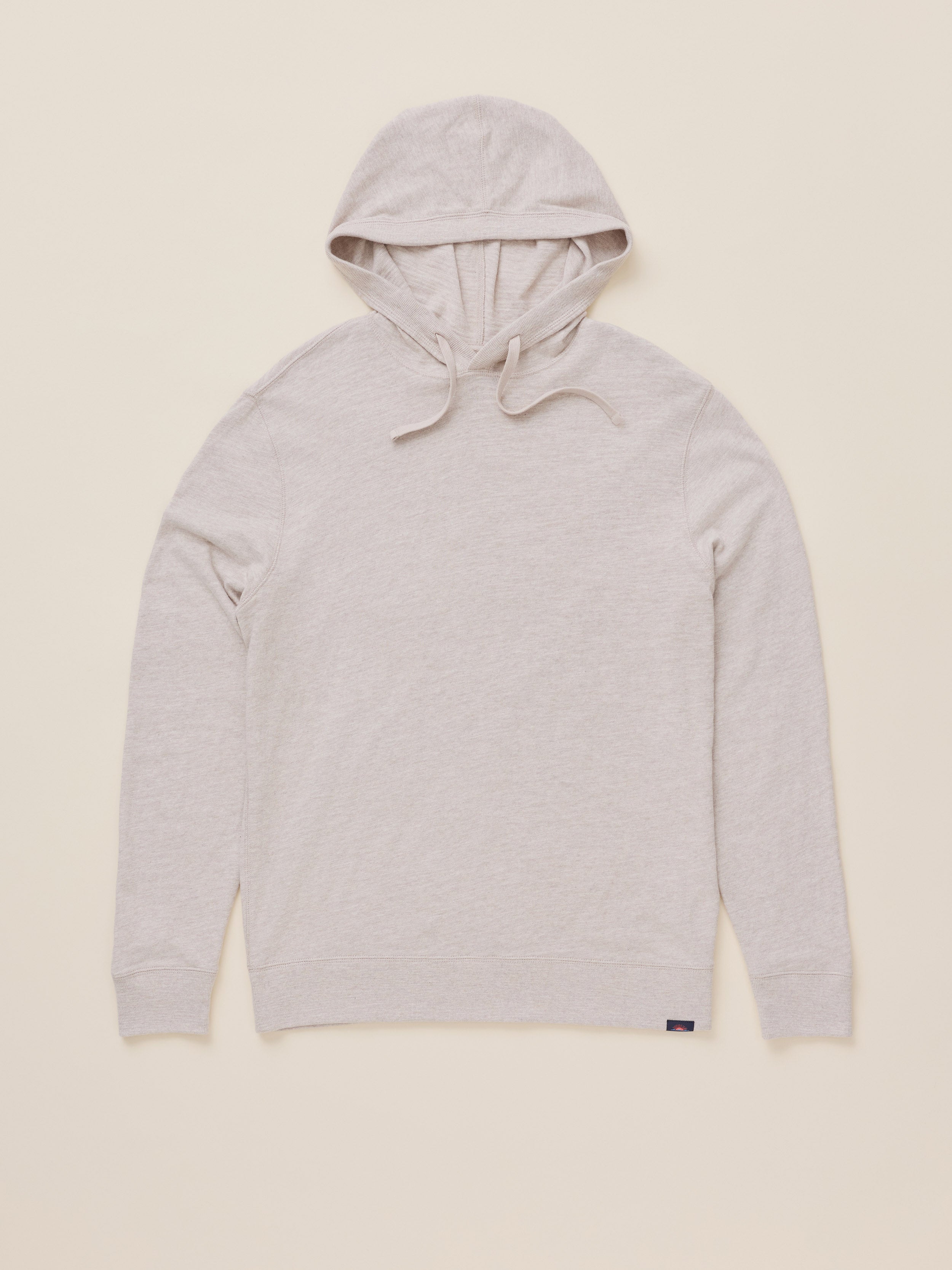 A light heather gray pullover hoodie with drawstrings, laid flat against a solid cream-colored background.