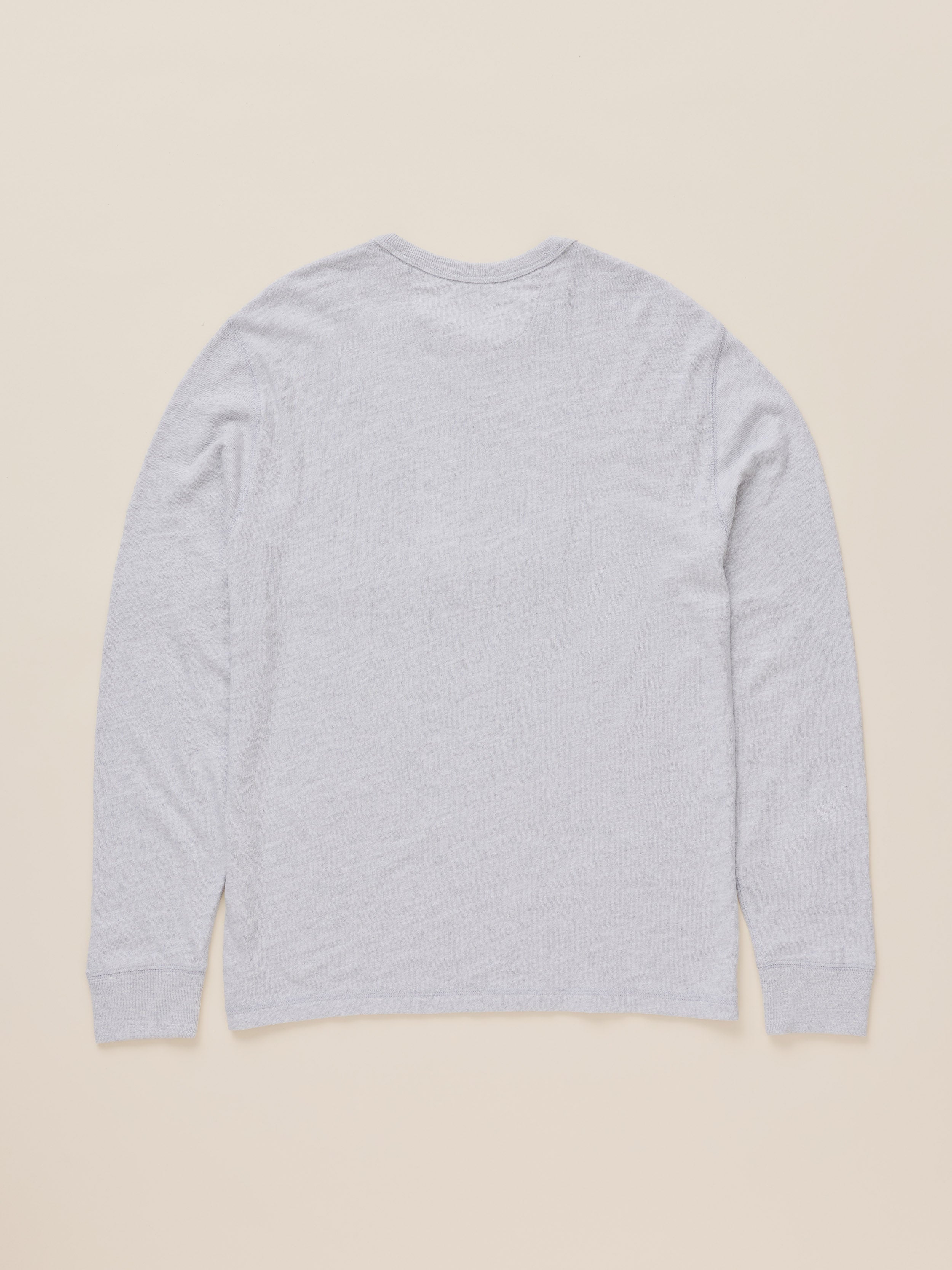 A light gray heather long-sleeve t-shirt shown from the back, laid flat against a solid beige background.