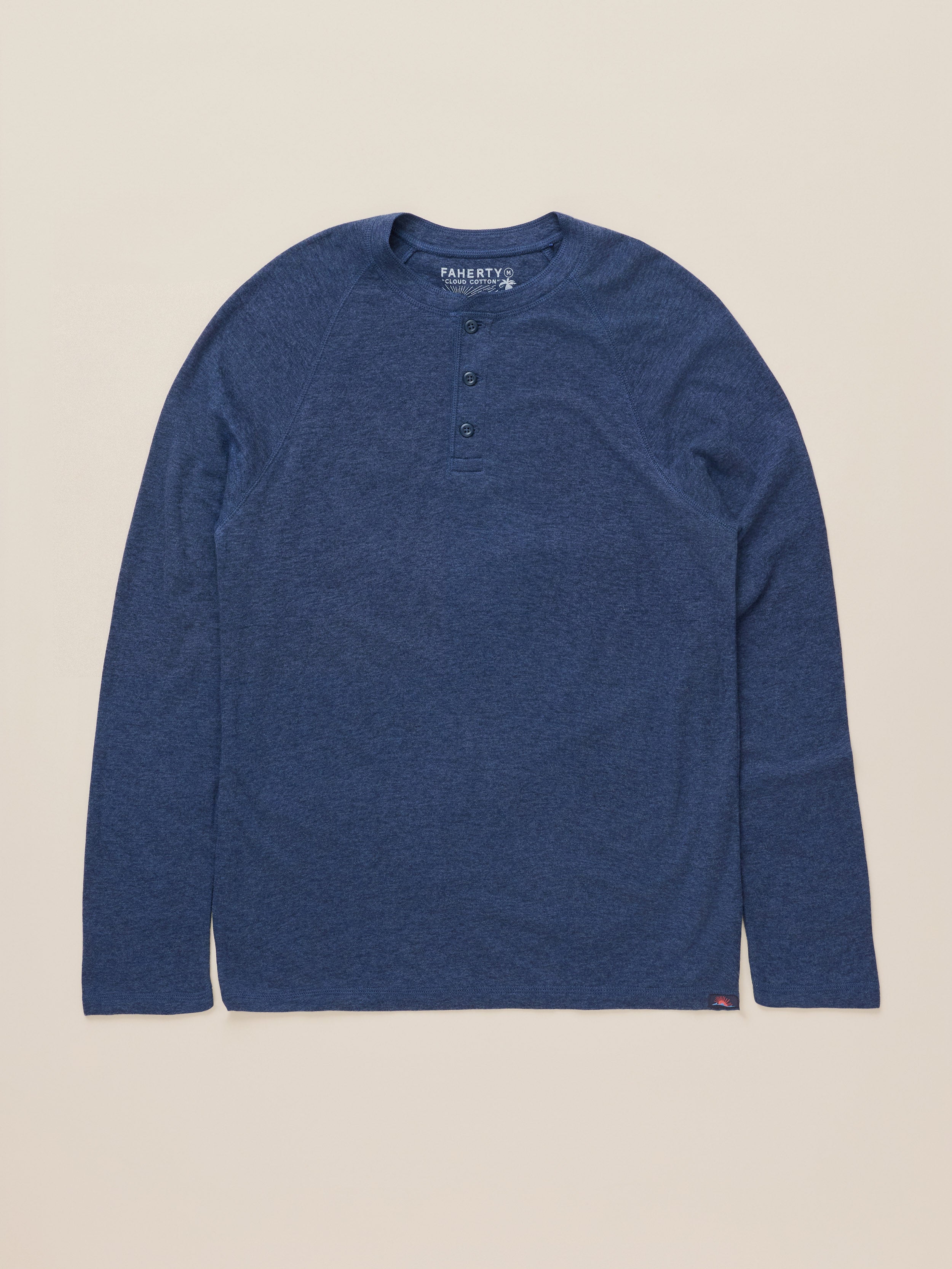 A heathered blue long-sleeve henley shirt with three buttons, laid flat on a light beige background. The brand name 'FAHERTY' is visible on the inner neck label.