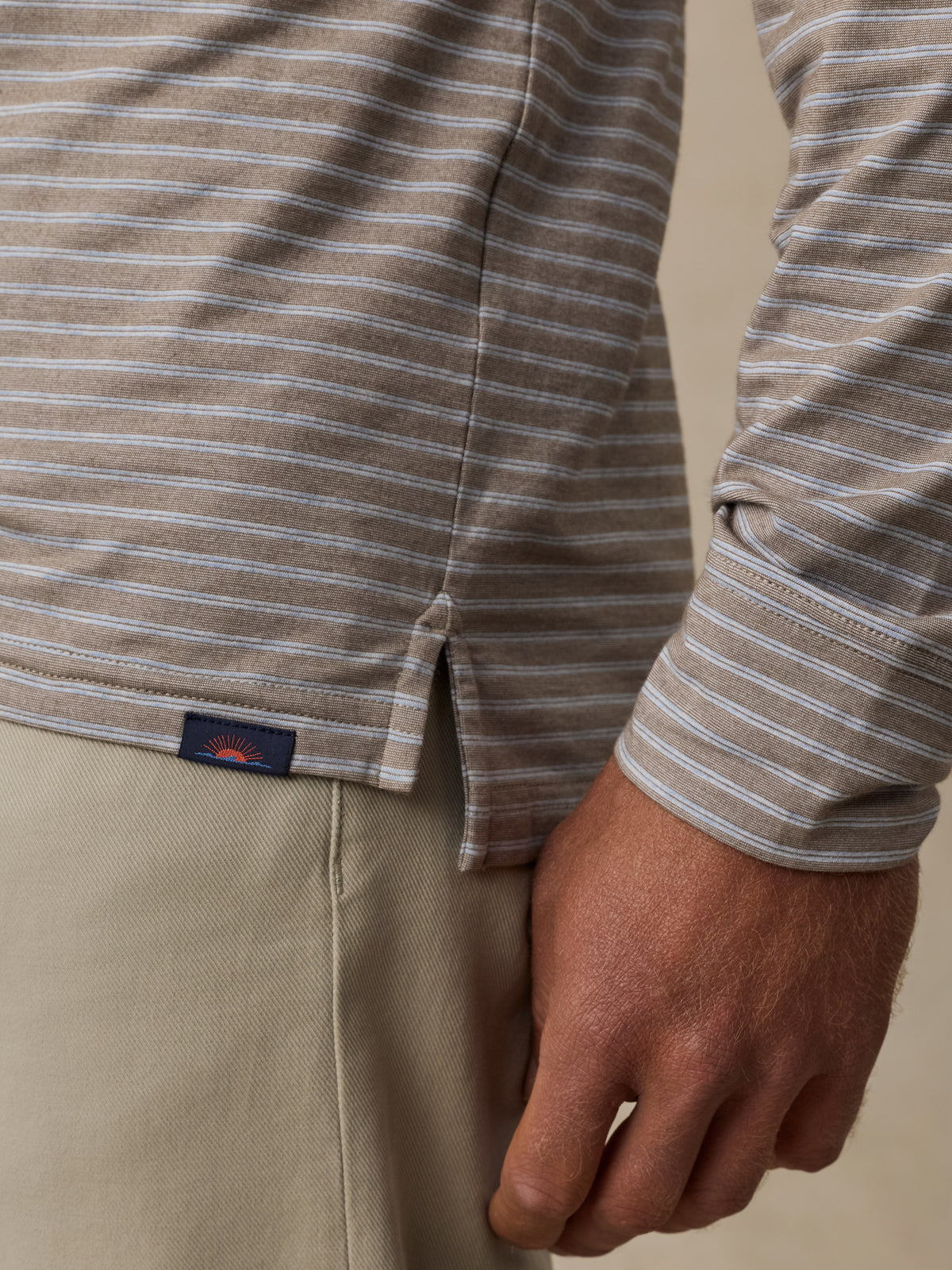 Close up of a man wearing a long-sleeve collared polo shirt and khaki pants, image 4 of 6