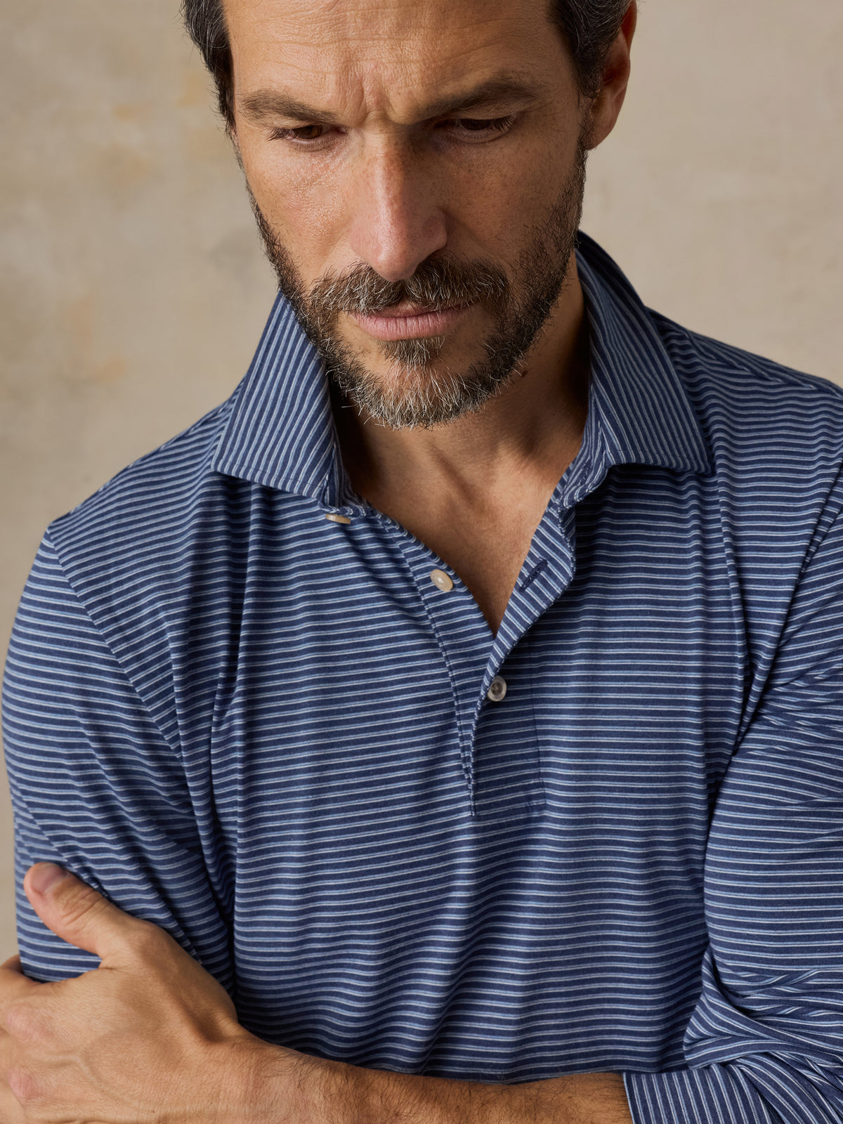 Close up of a man wearing a blue striped polo shirt, image 4 of 5