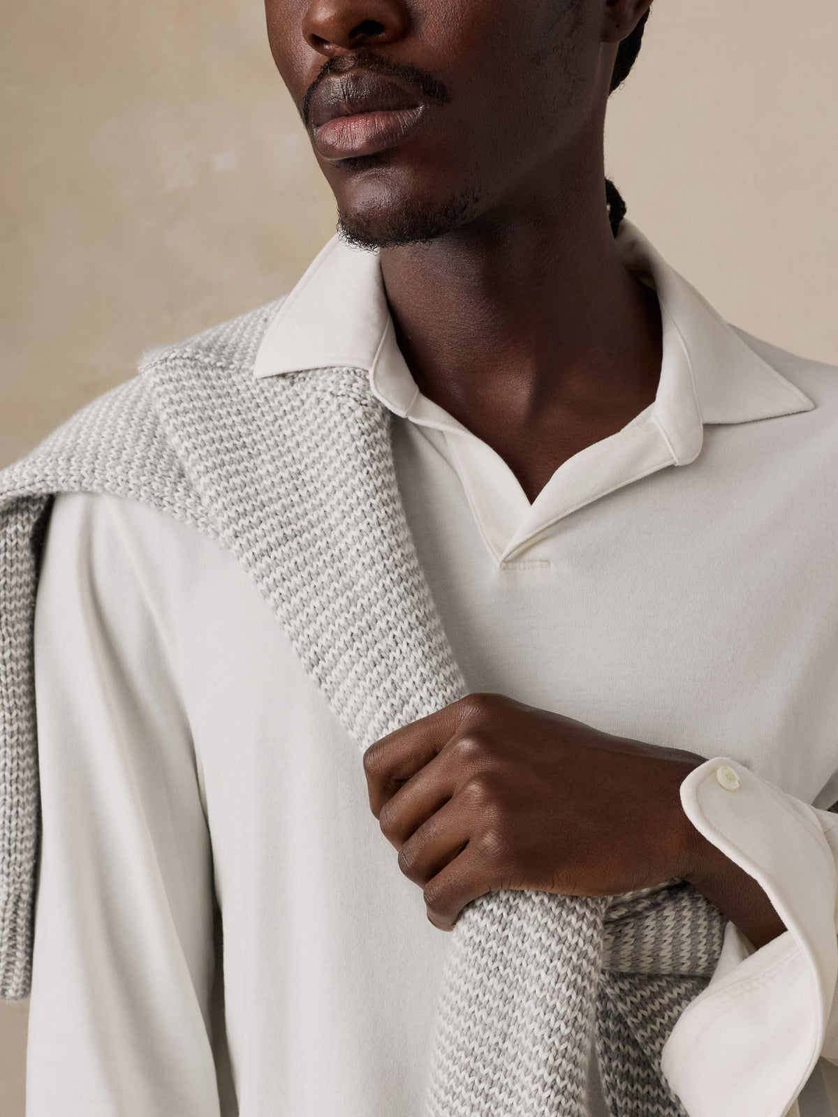 Close up of a  man wearing a white long sleeve polo and a grey and white sweater , image 3 of 6