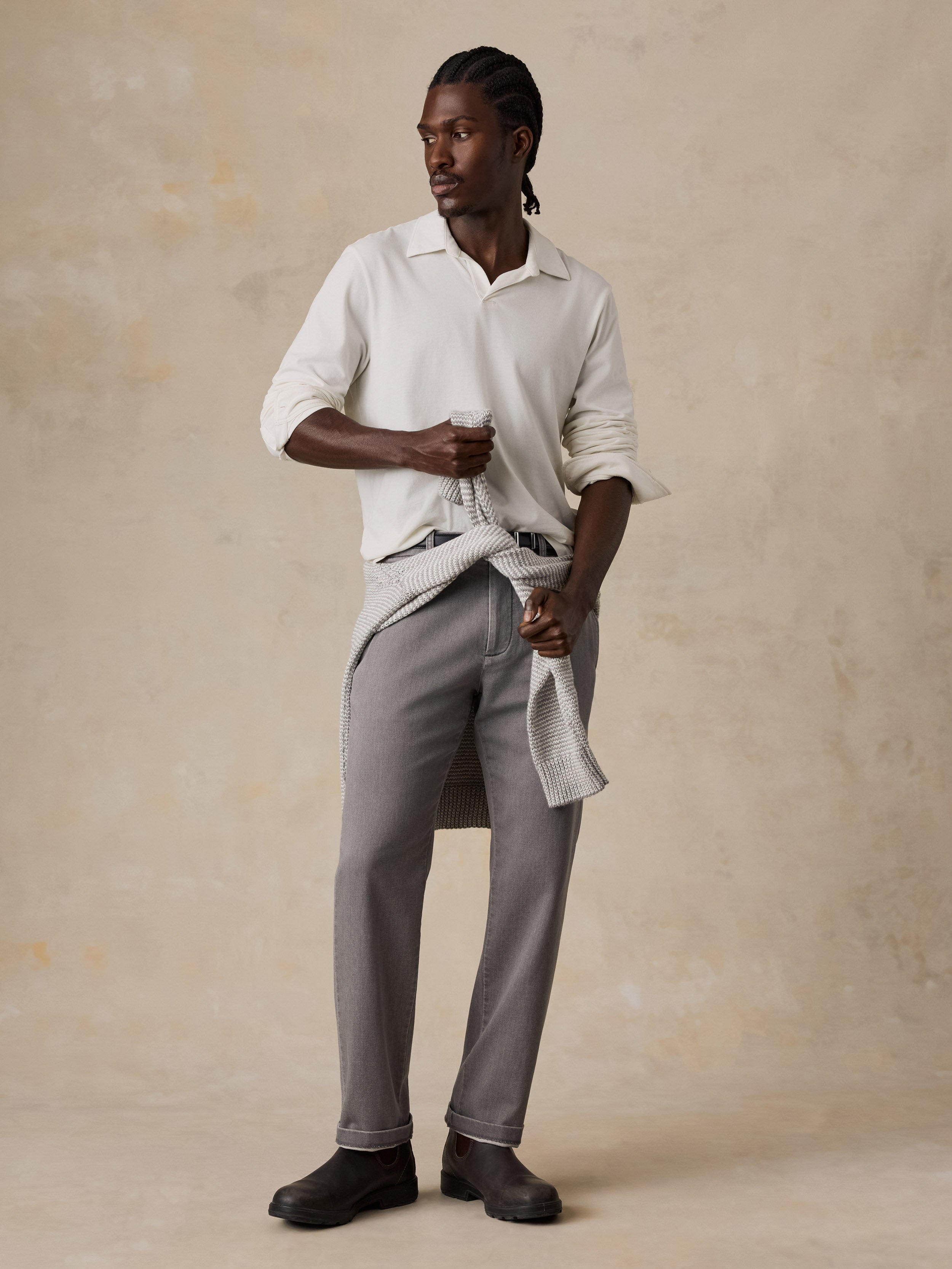 A man wearing a white long sleeve polo and grey pants