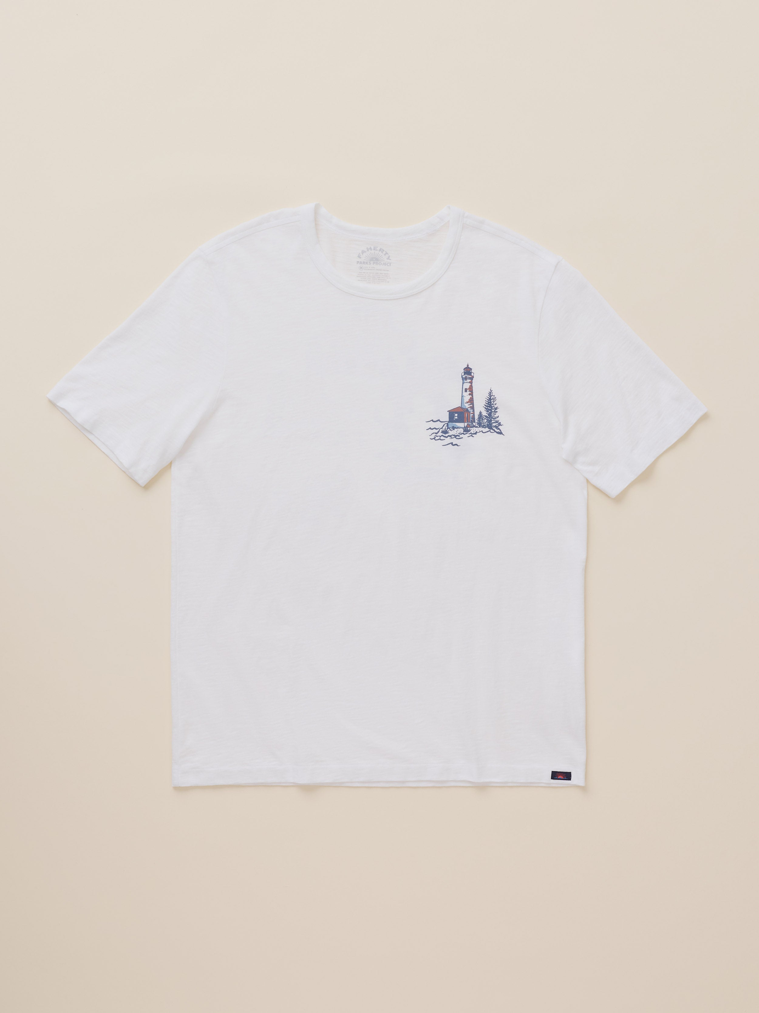 A white short-sleeve crewneck t-shirt with a small lighthouse graphic printed on the left chest, displayed flat against a light beige background.