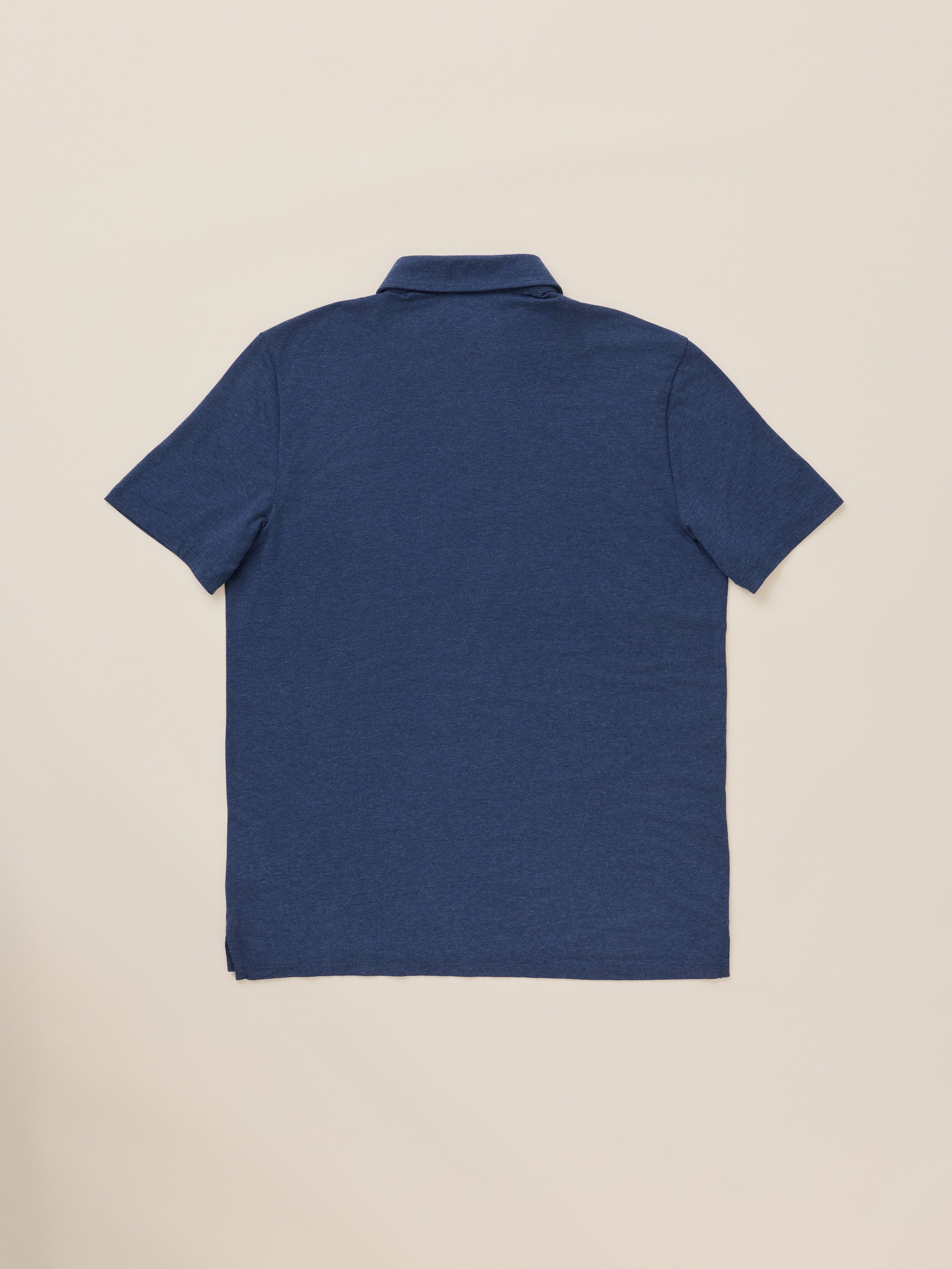 A blue short-sleeve polo shirt against a warm beige studio background