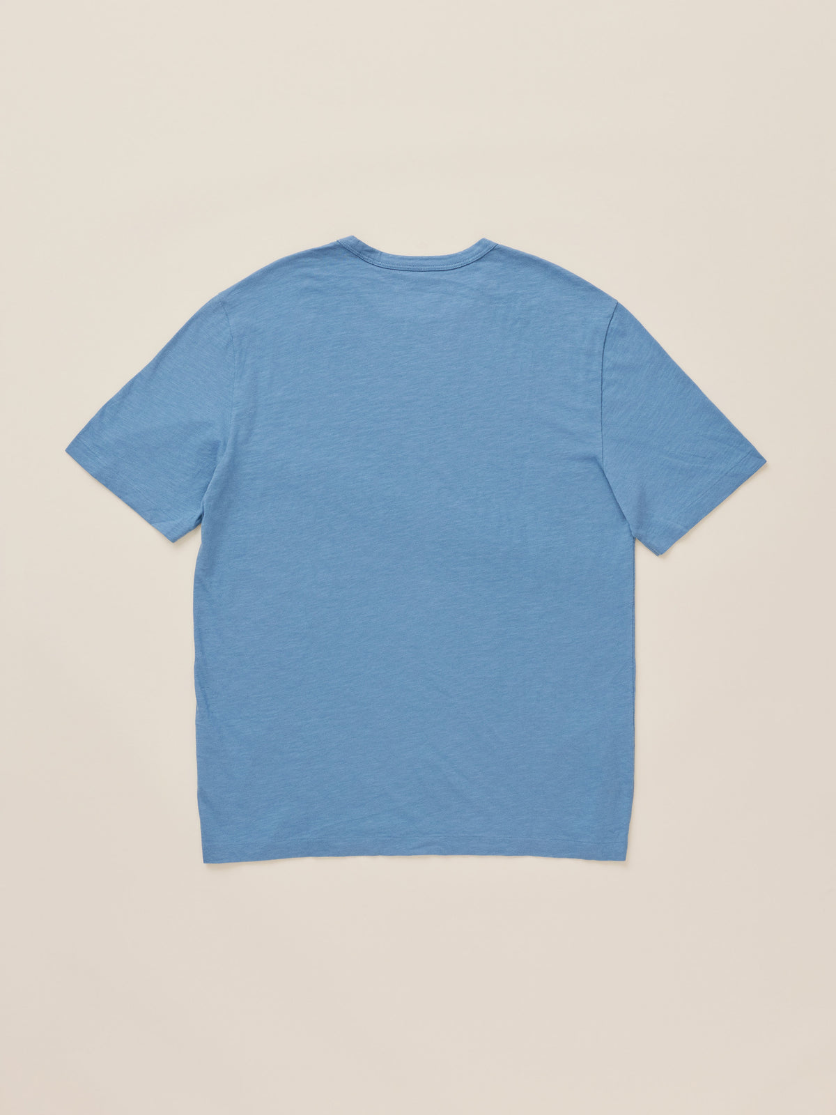 A light blue short-sleeve crewneck t-shirt shown from the back, laid flat against a solid beige background., image 7 of 7