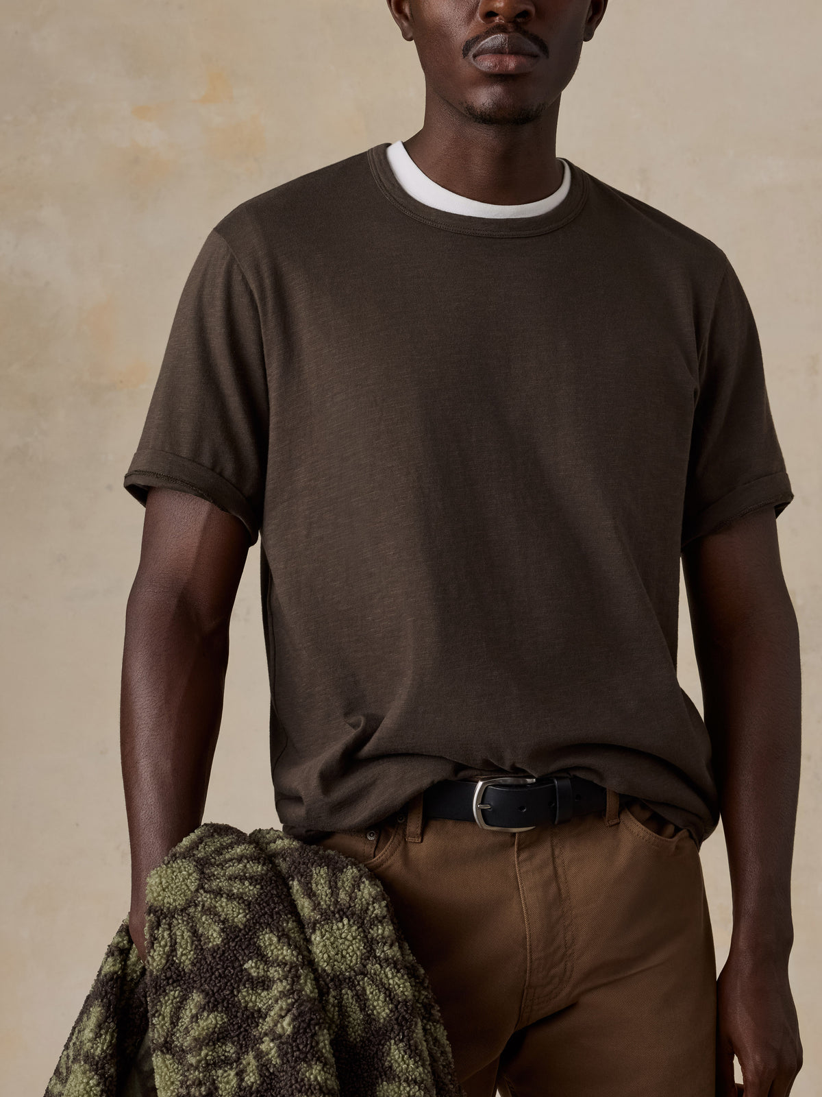 A man wearing a brown t-shirt and brown pants, image 4 of 6