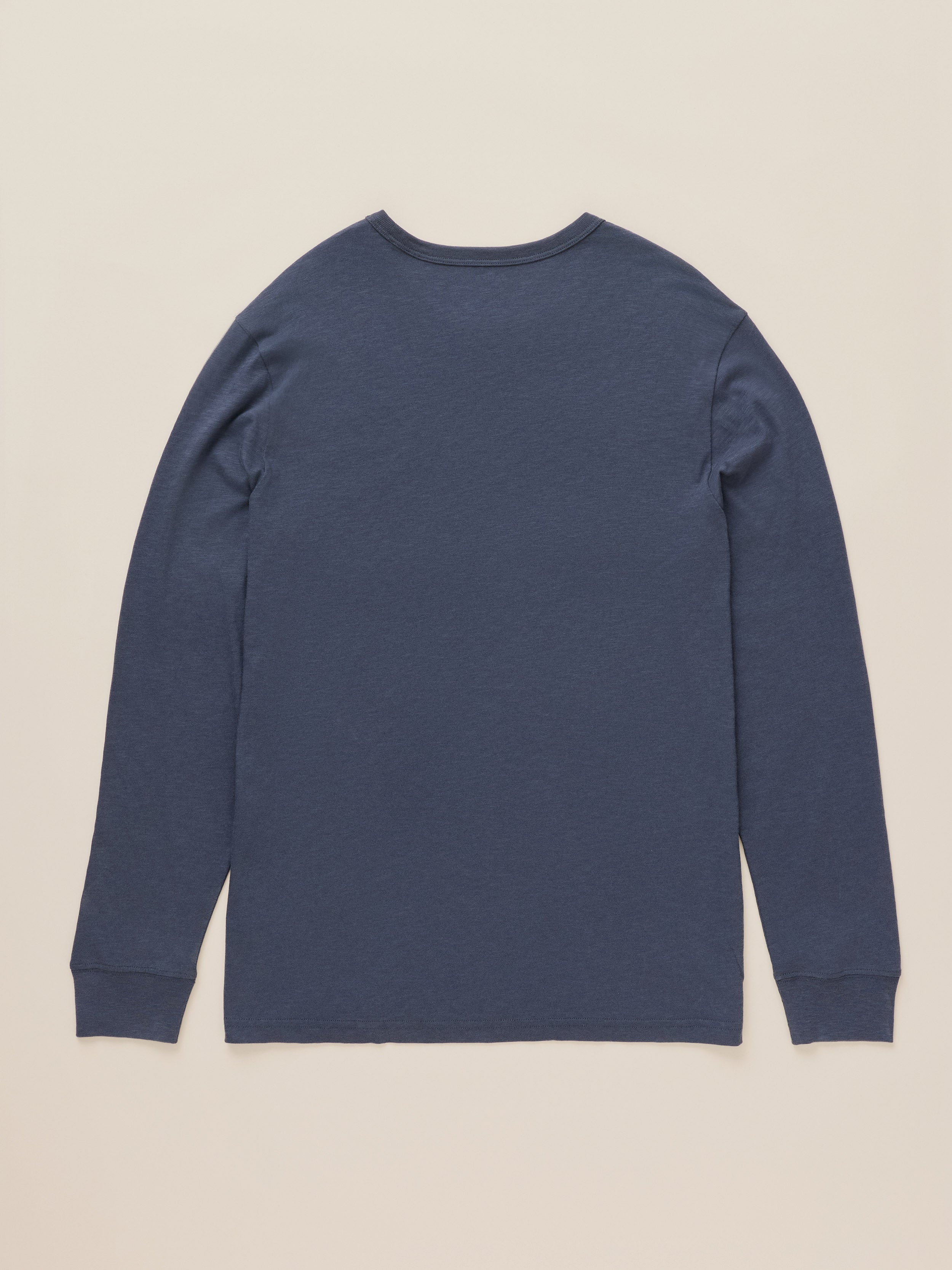 A navy blue long-sleeve crewneck shirt shown from the back, laid flat against a light beige background.