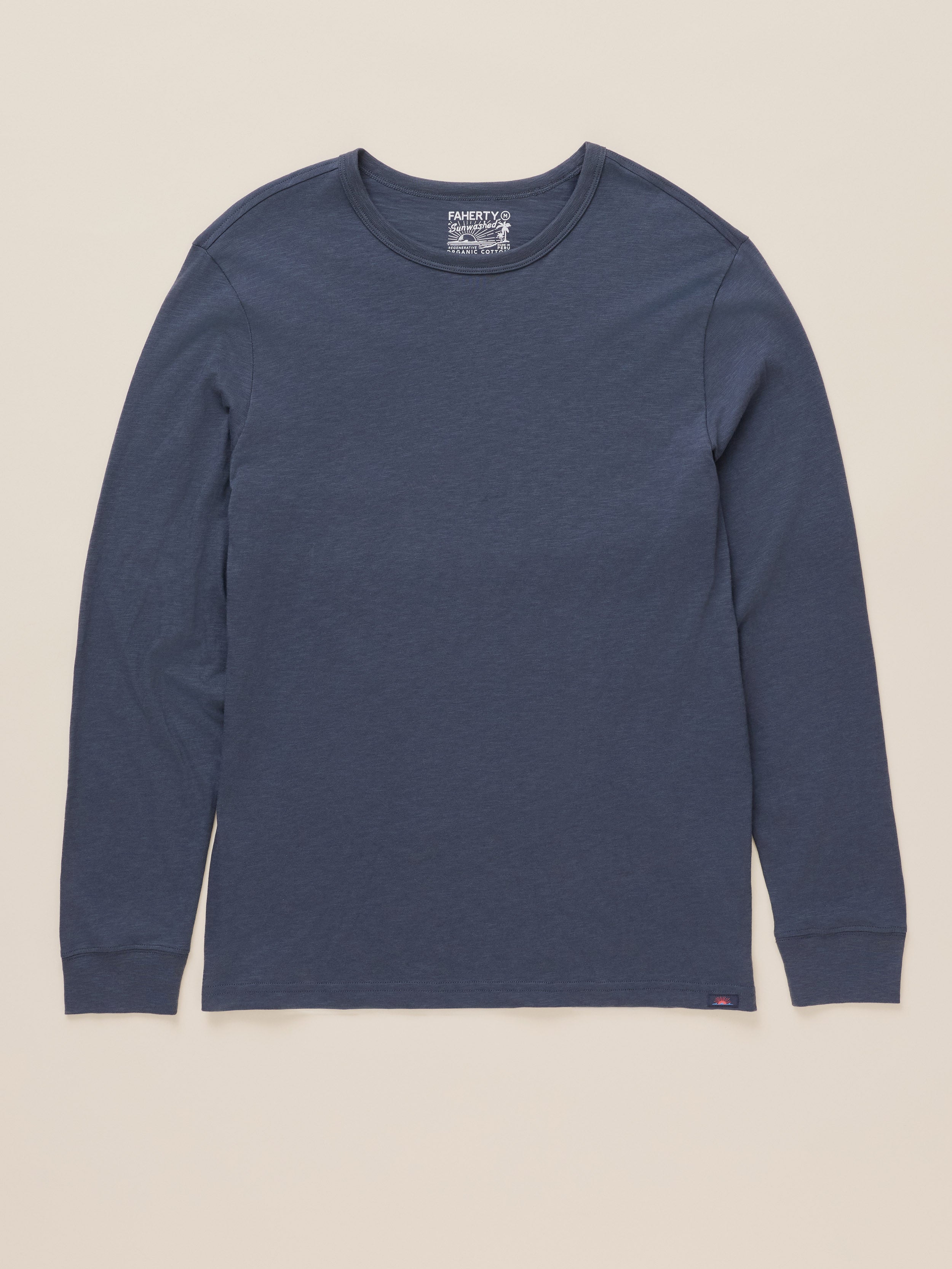 A dark blue long-sleeve crewneck shirt by Port & Company, laid flat against a light beige background.