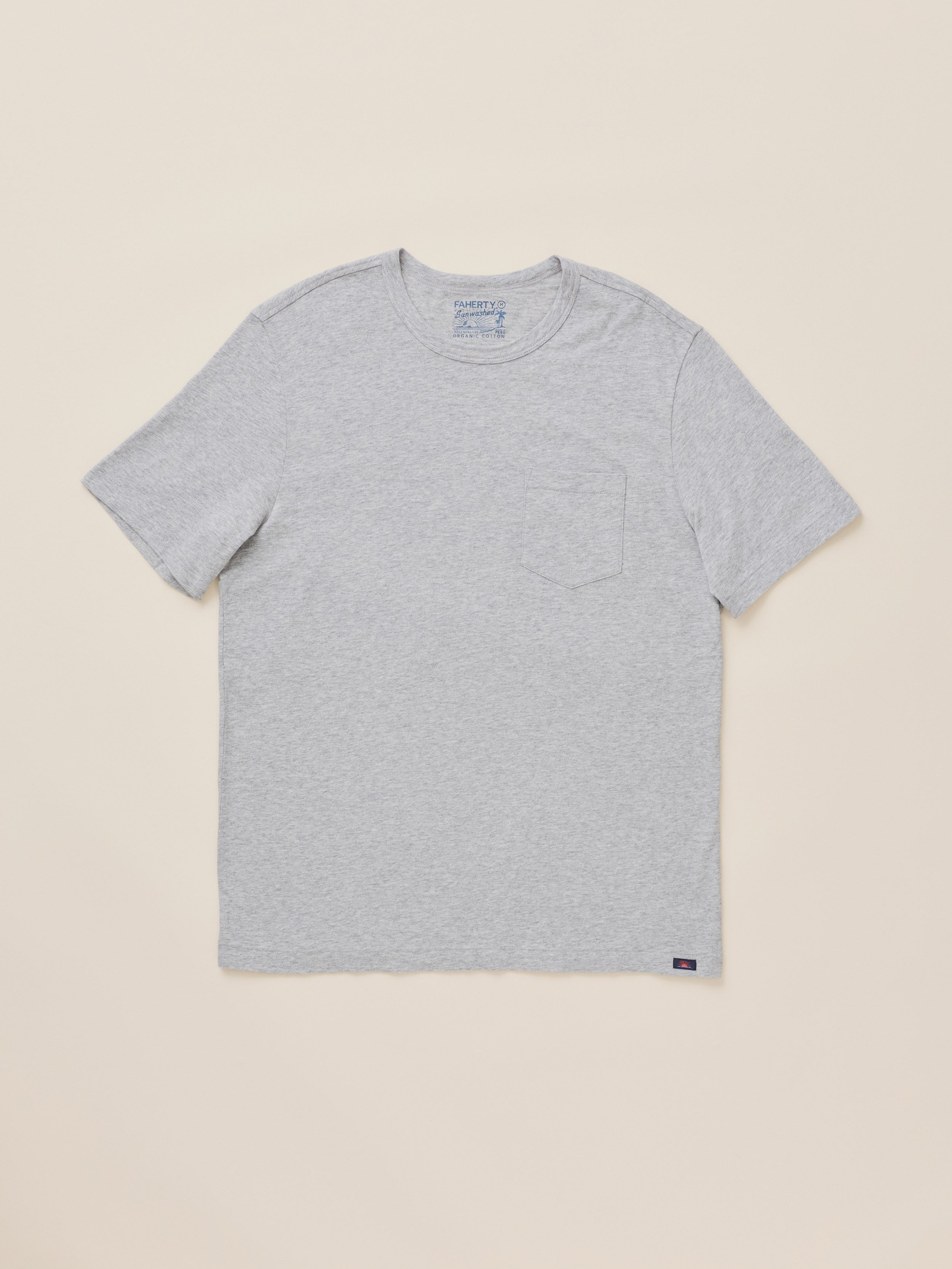 A light gray heather short-sleeve crewneck t-shirt with a left chest pocket, laid flat on a warm beige background.
