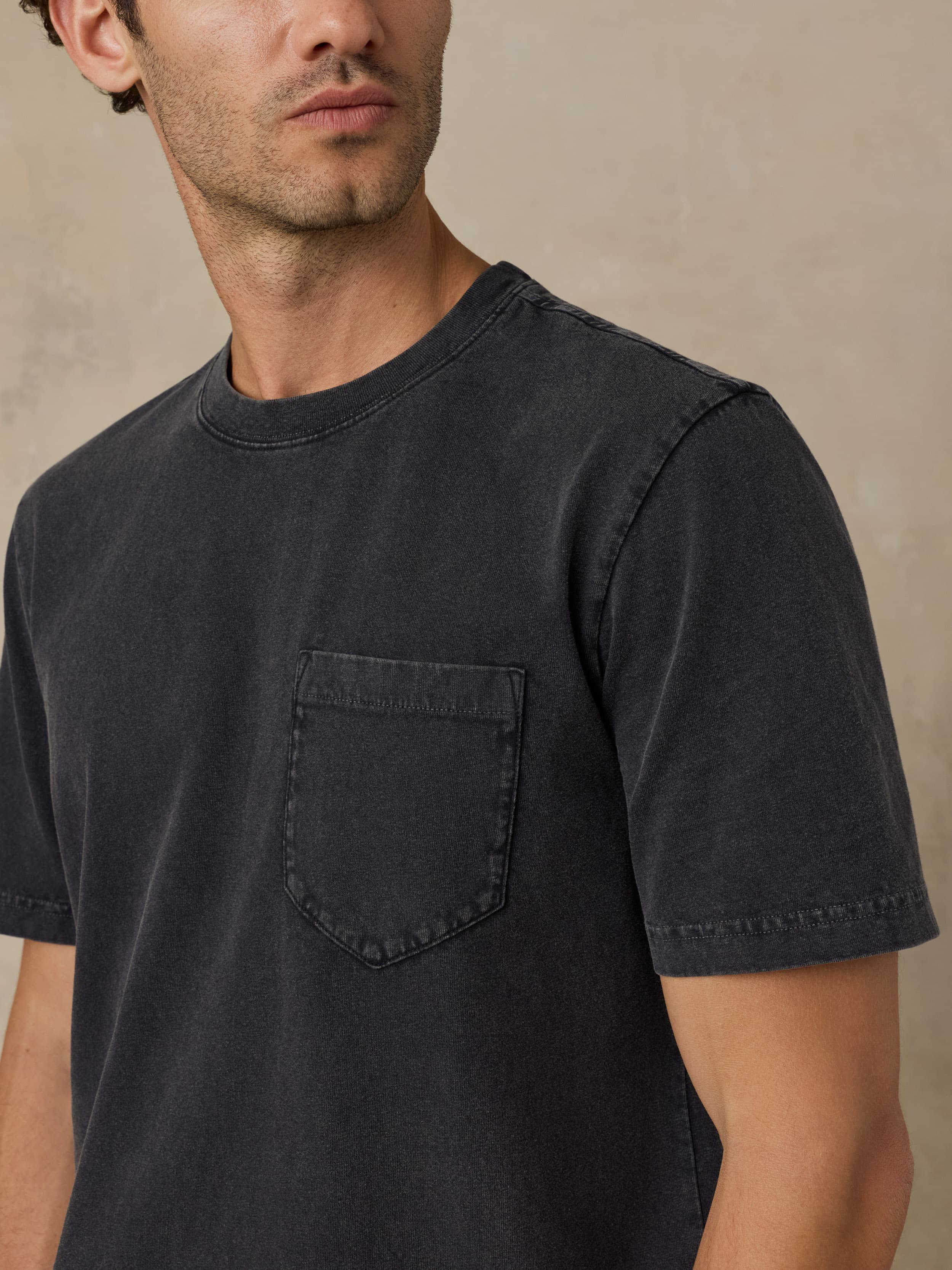 Man wearing a black t-shirt against a beige background