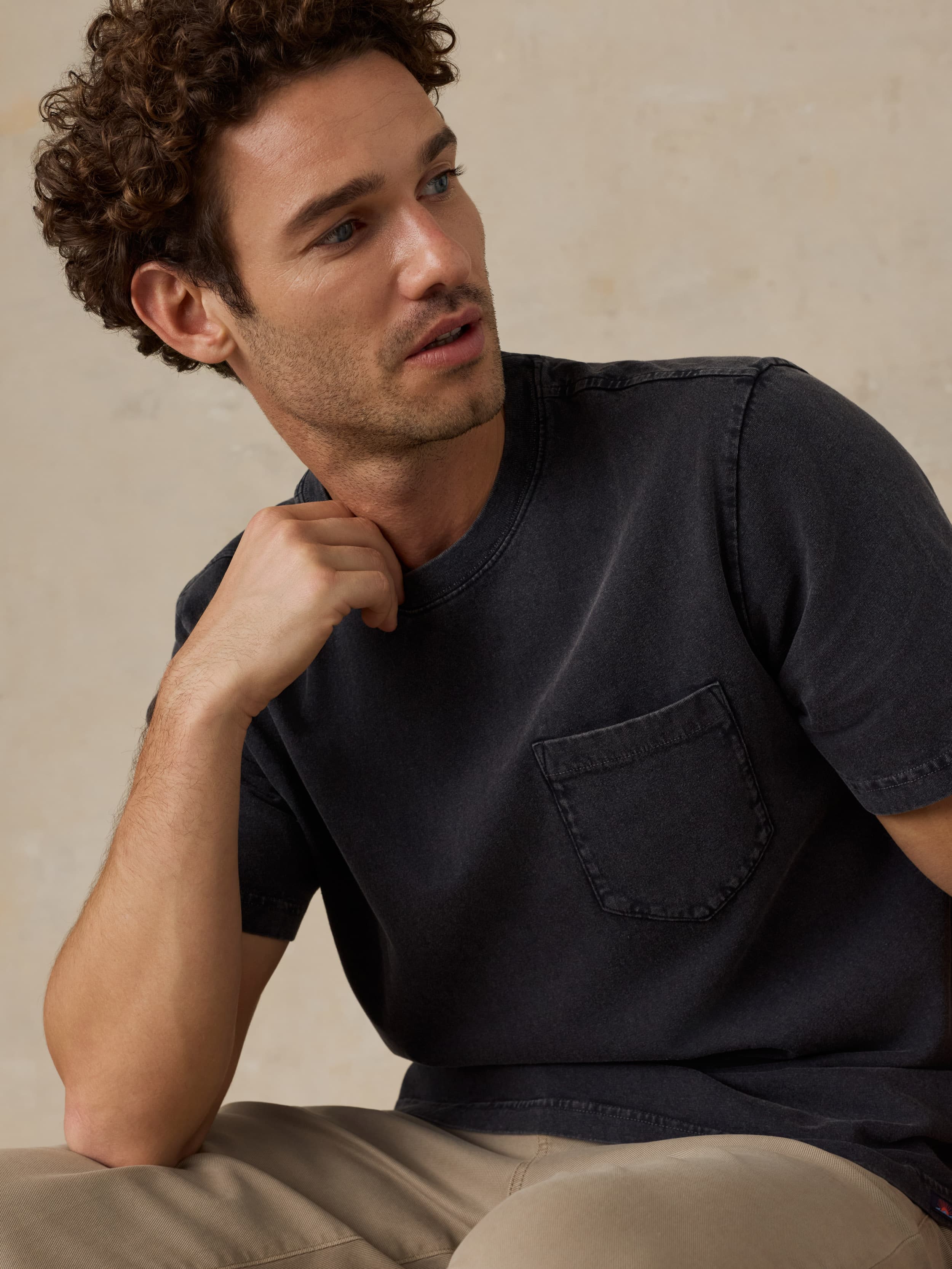 Man wearing a black t-shirt against a beige background
