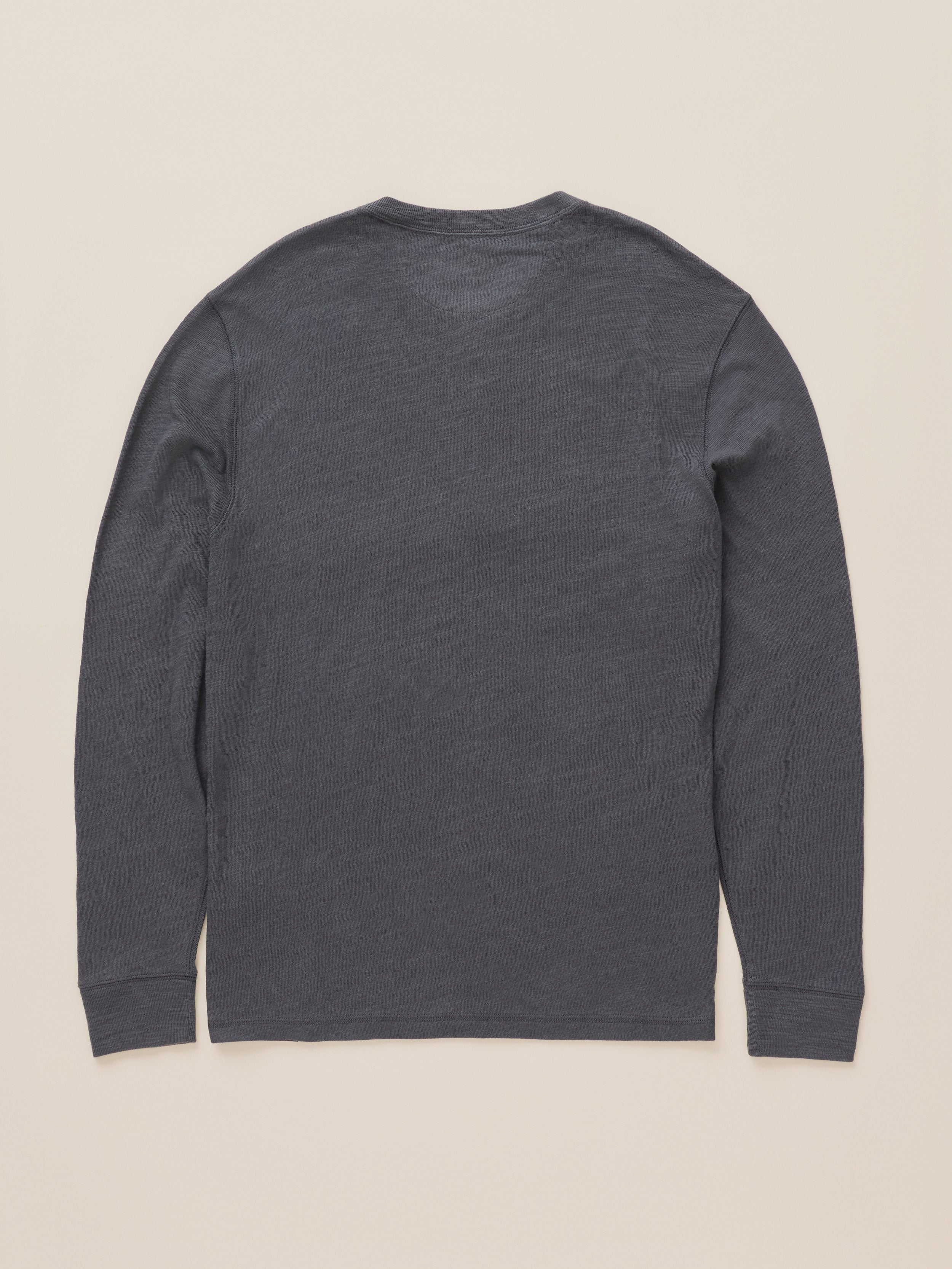 A dark gray long-sleeve shirt shown from the back, laid flat against a light beige background.