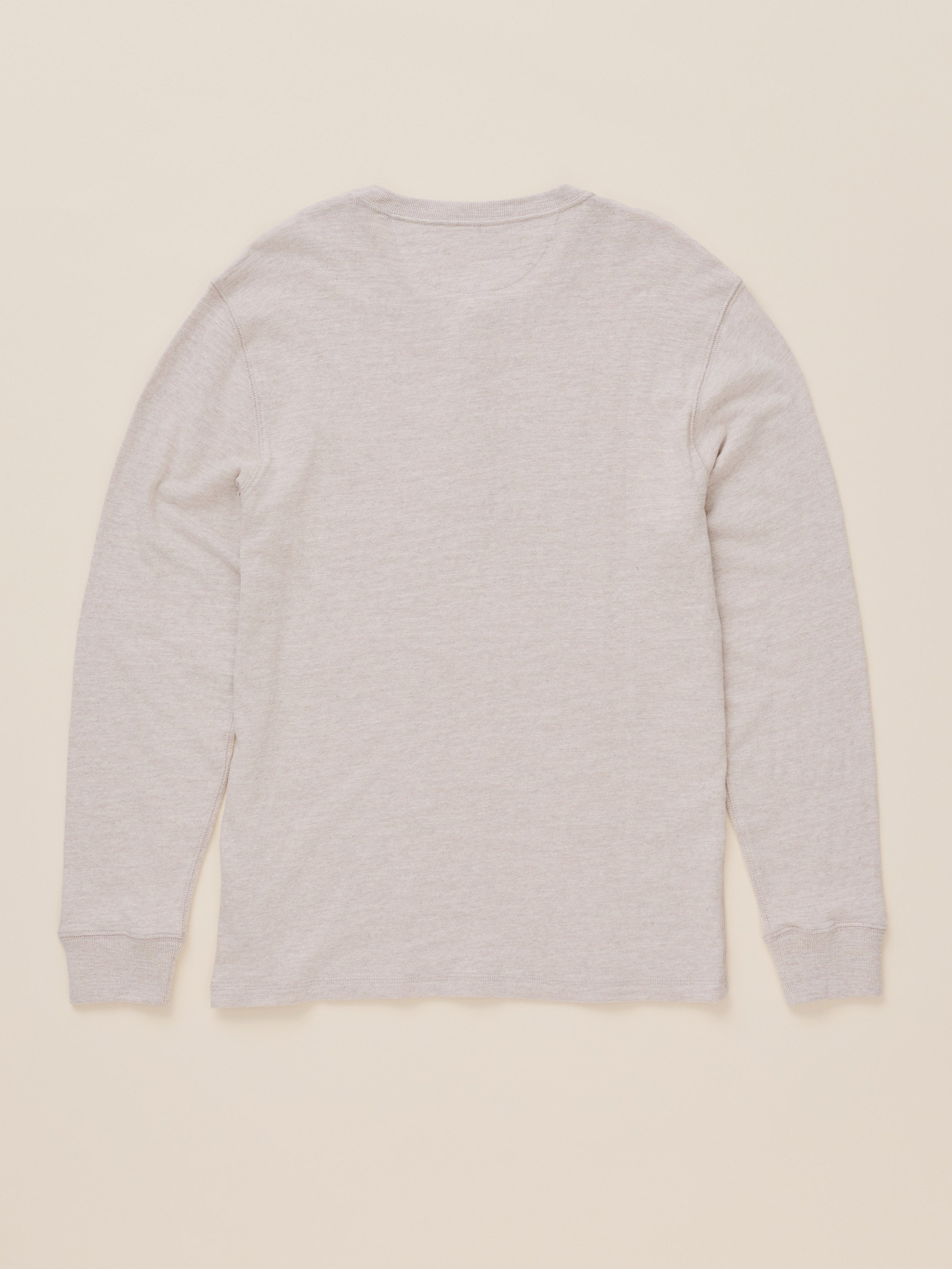 A light oatmeal heather long-sleeve t-shirt shown from the back, laid flat against a solid cream-colored background.