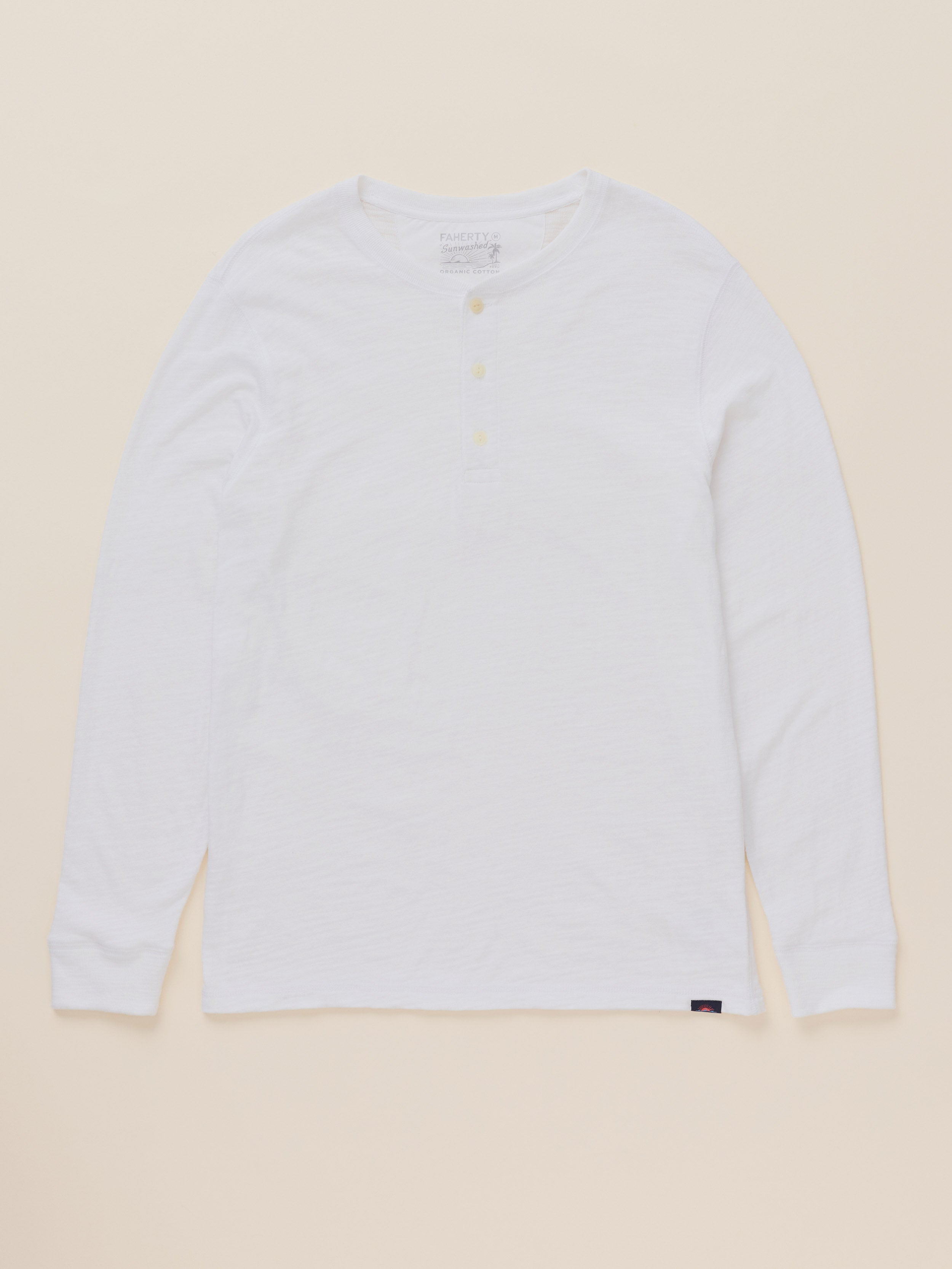A white long-sleeve henley shirt with a three-button placket, laid flat against a light beige background.