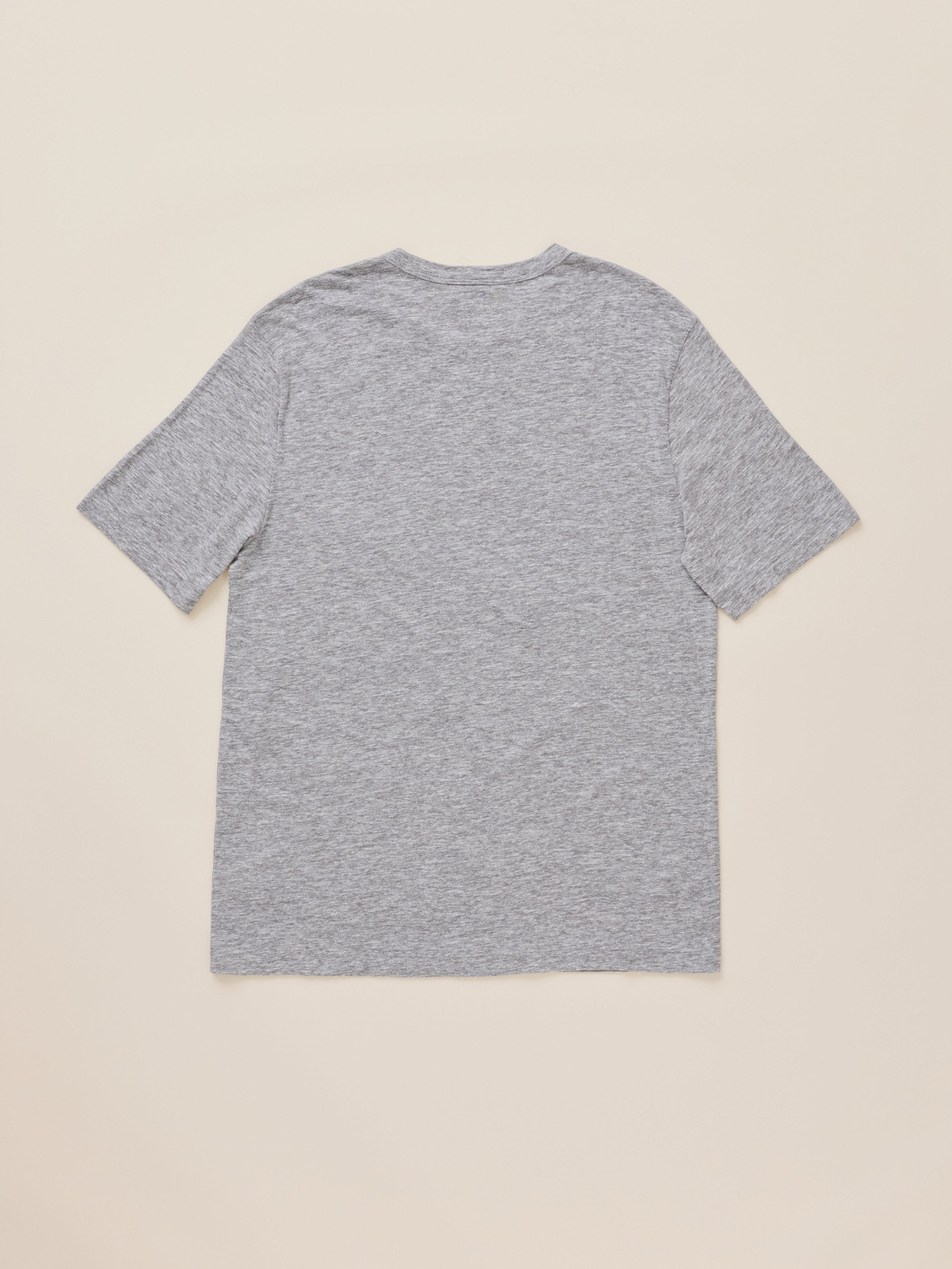 A heather gray short-sleeve t-shirt shown from the back, laid flat against a solid light beige background.