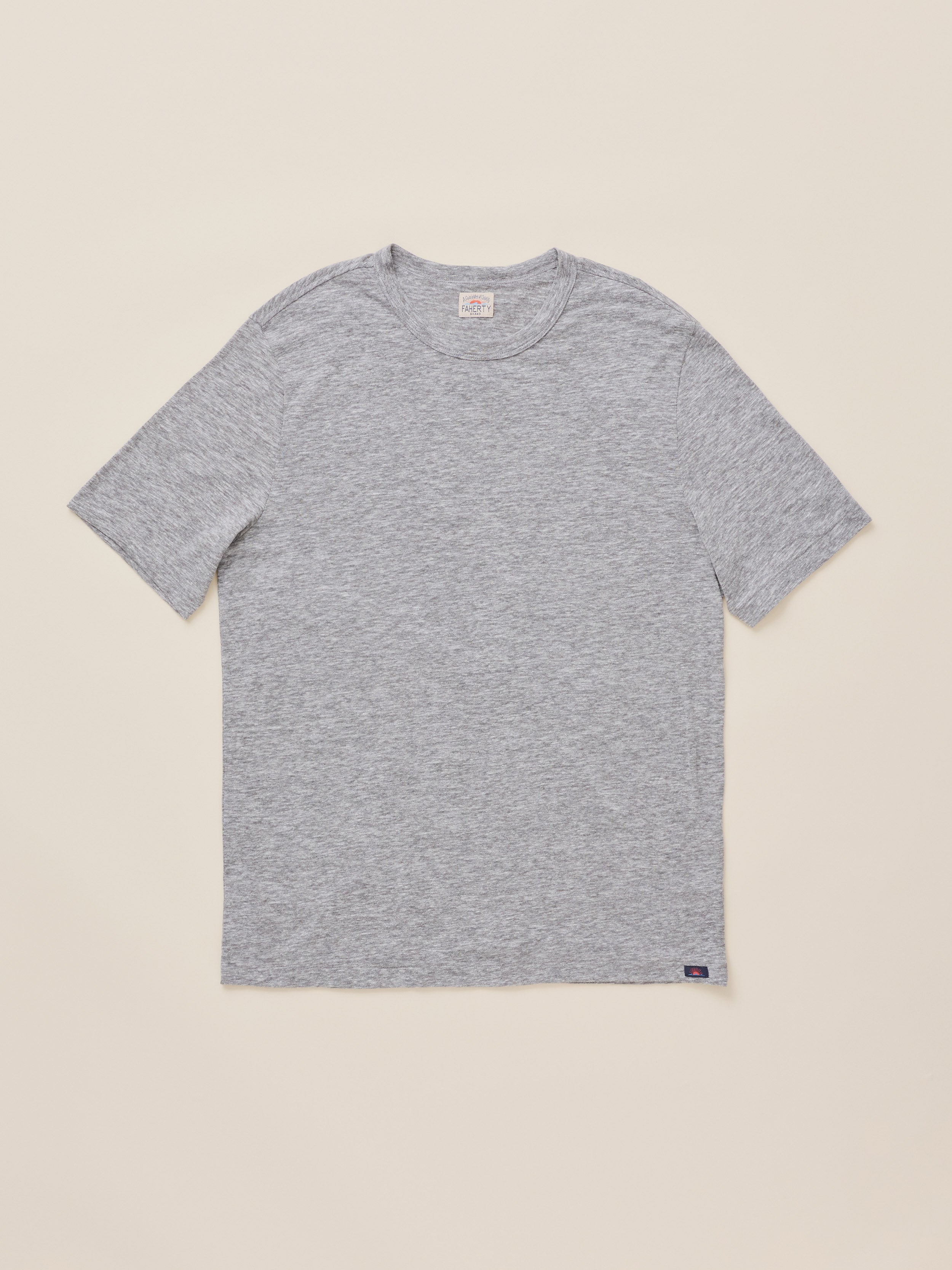 A classic short-sleeve crewneck t-shirt in heather gray, laid flat against a solid light beige background.