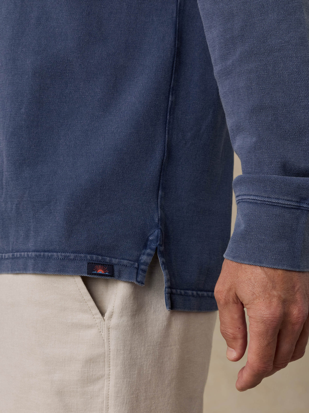 Close-up of a man wearing a blue shirt with a Faherty brand logo and beige shorts, image 5 of 6