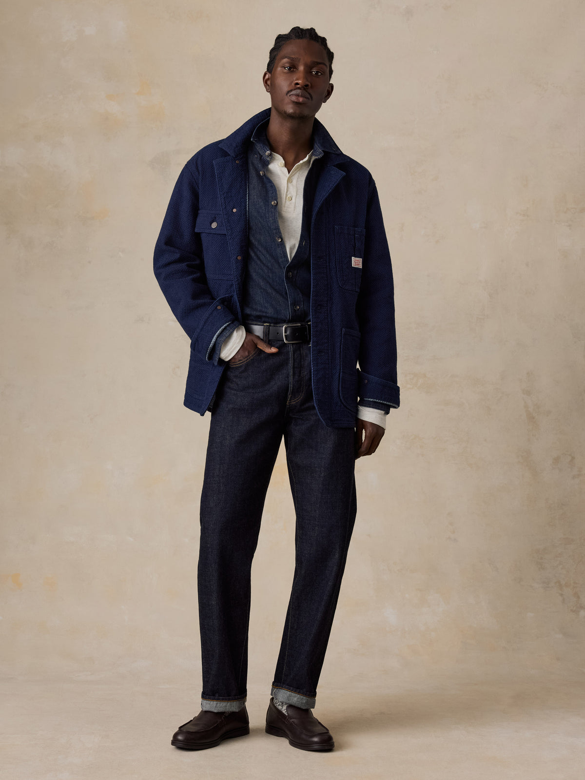 A man wearing a blue jacket over a denim shirt, blue jeans, and loafers, image 6 of 6