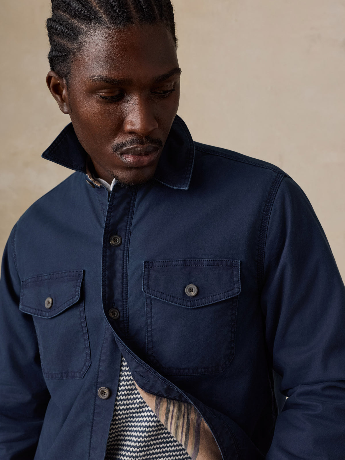 Close up of a man wearing a blue jacket over a blue striped sweater , image 4 of 5