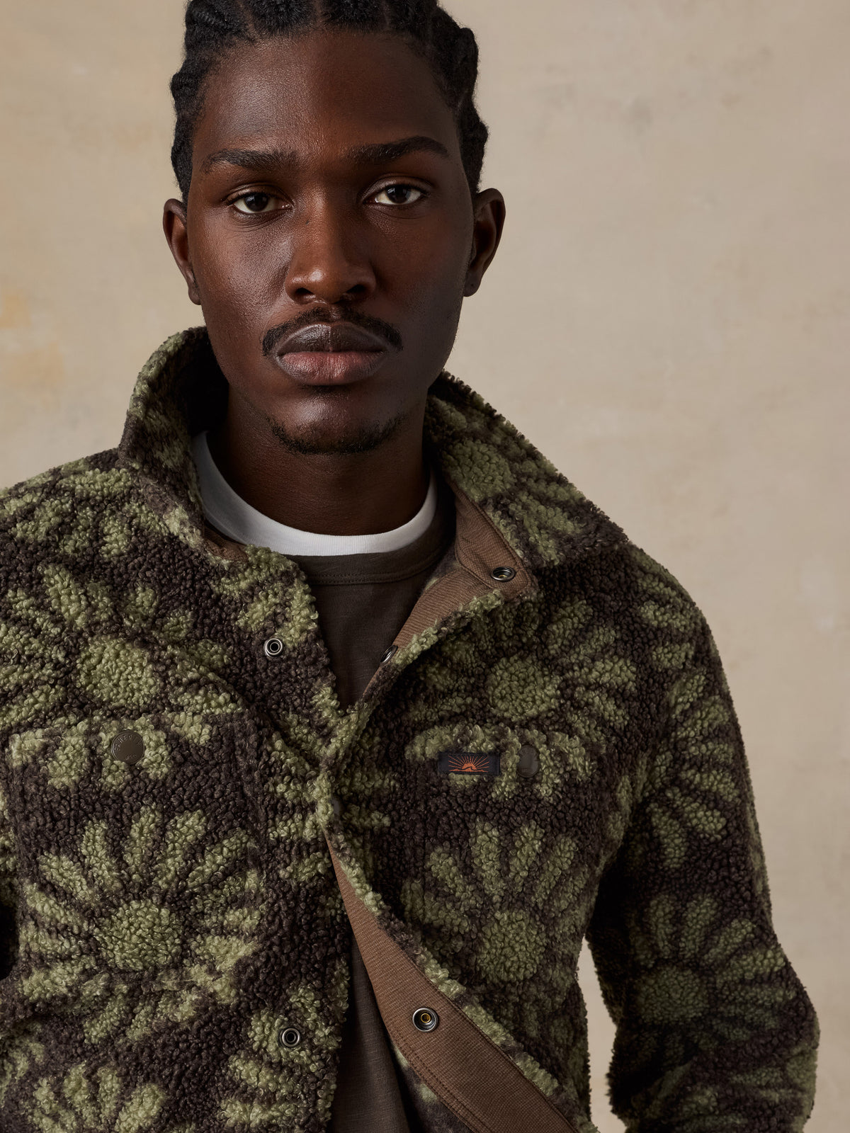 Close up of a man wearing a floral fleece jacket over a brown tee, image 4 of 7