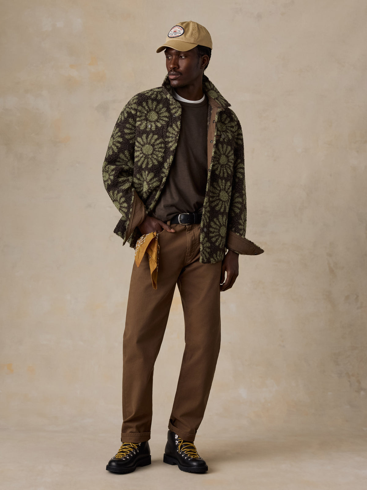 A man wearing a floral fleece jacket over a brown tee and brown pants, image 2 of 7