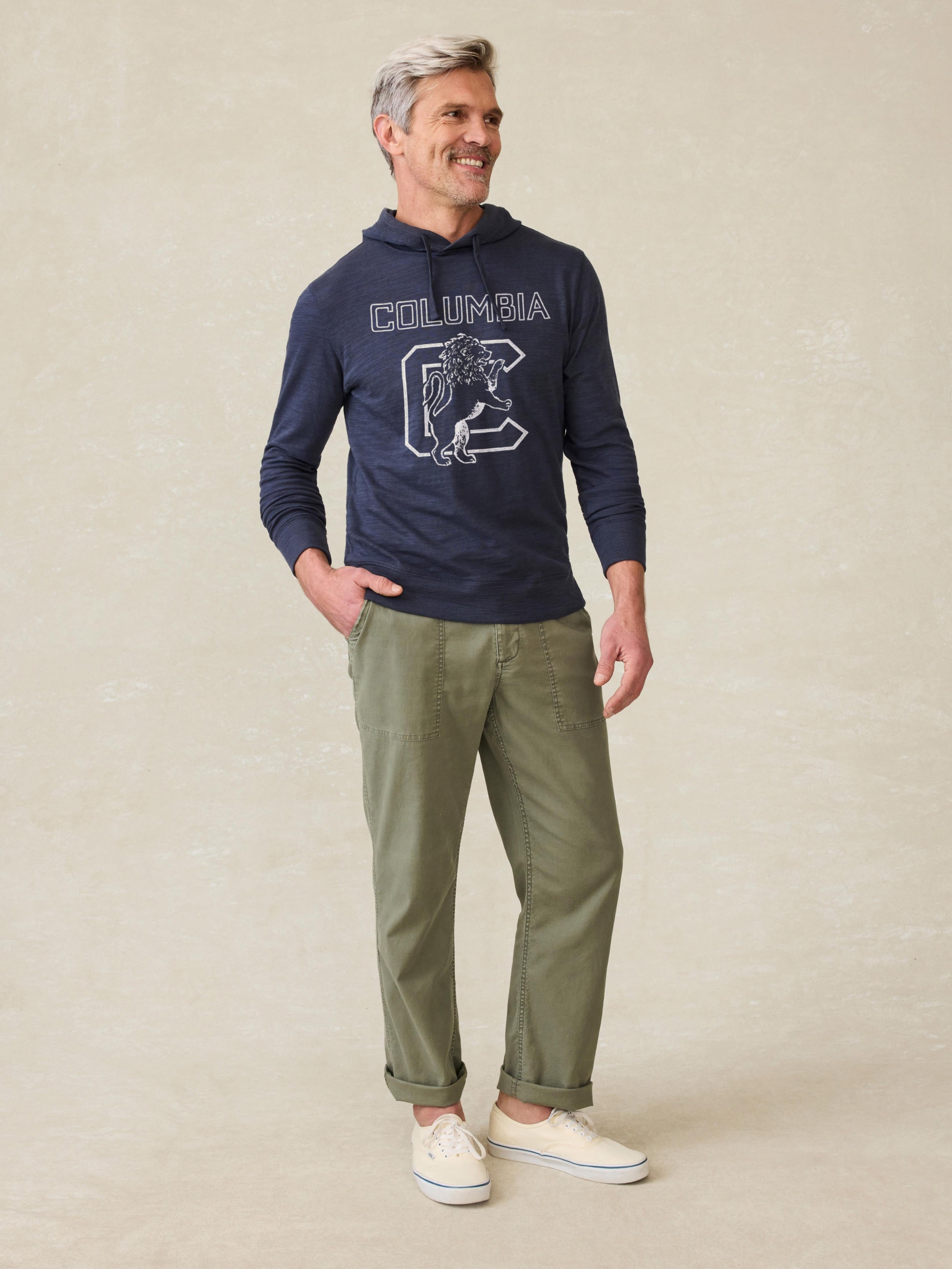 Man wearing a navy hoodie with Columbia graphic on the center front against a beige background
