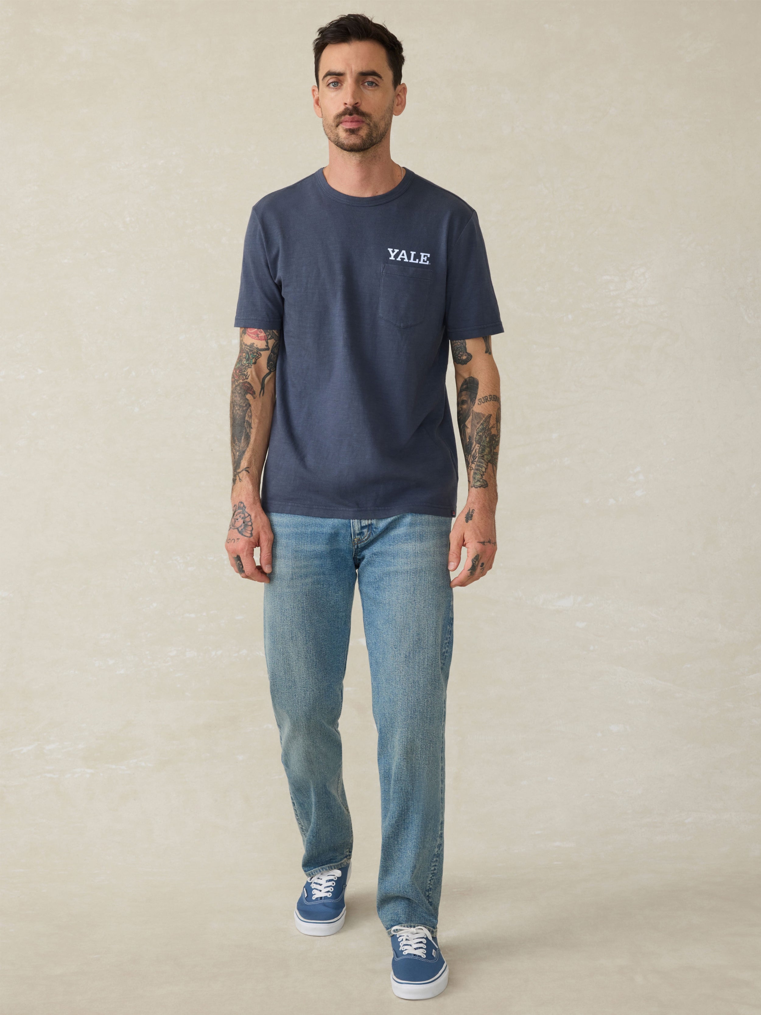 Man wearing a navy blue t-shirt with Yale graphic logo on a beige background