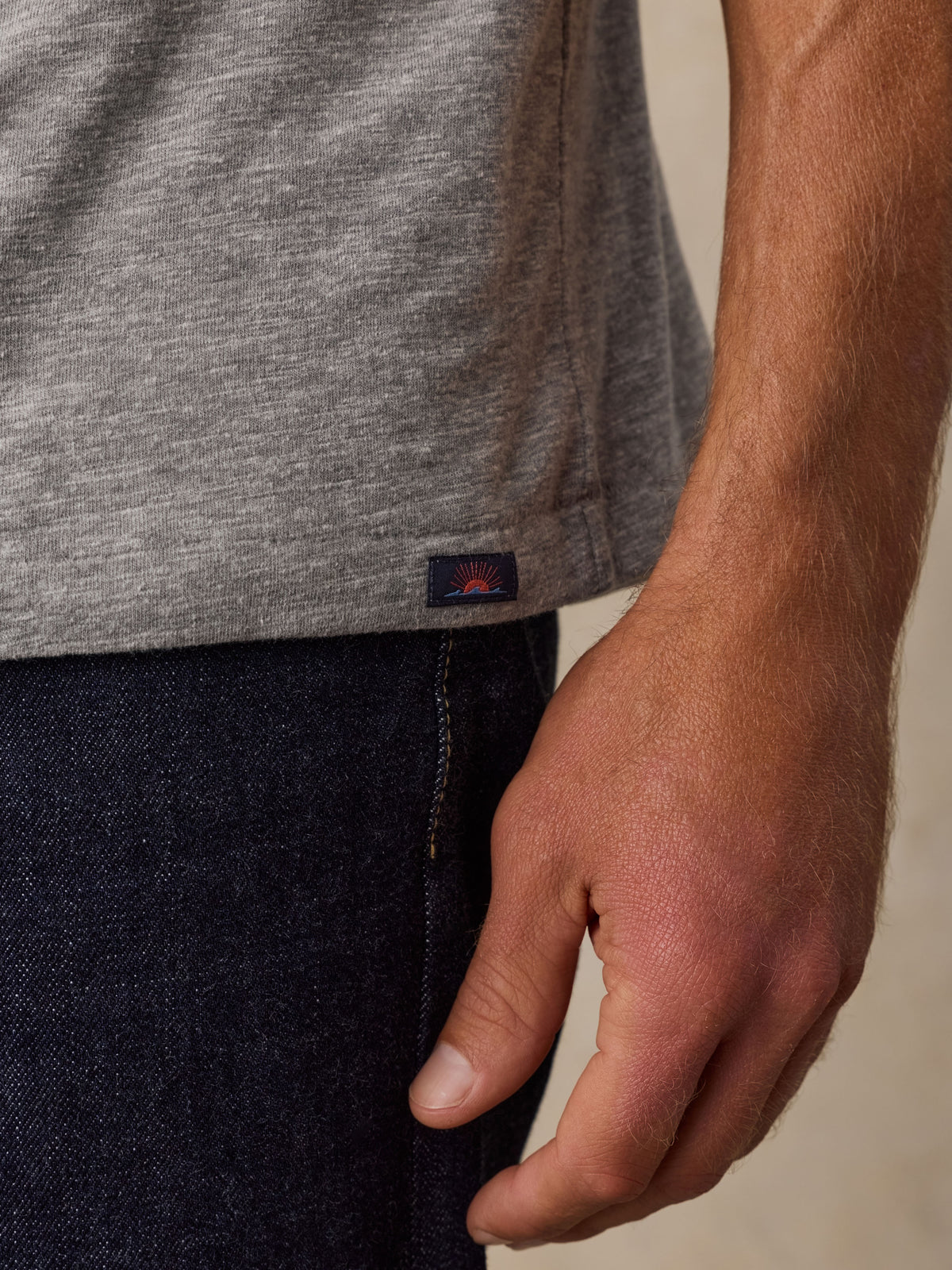 Close up of a man wearing a grey t-shirt with a Faherty brand label near the hem, image 5 of 6