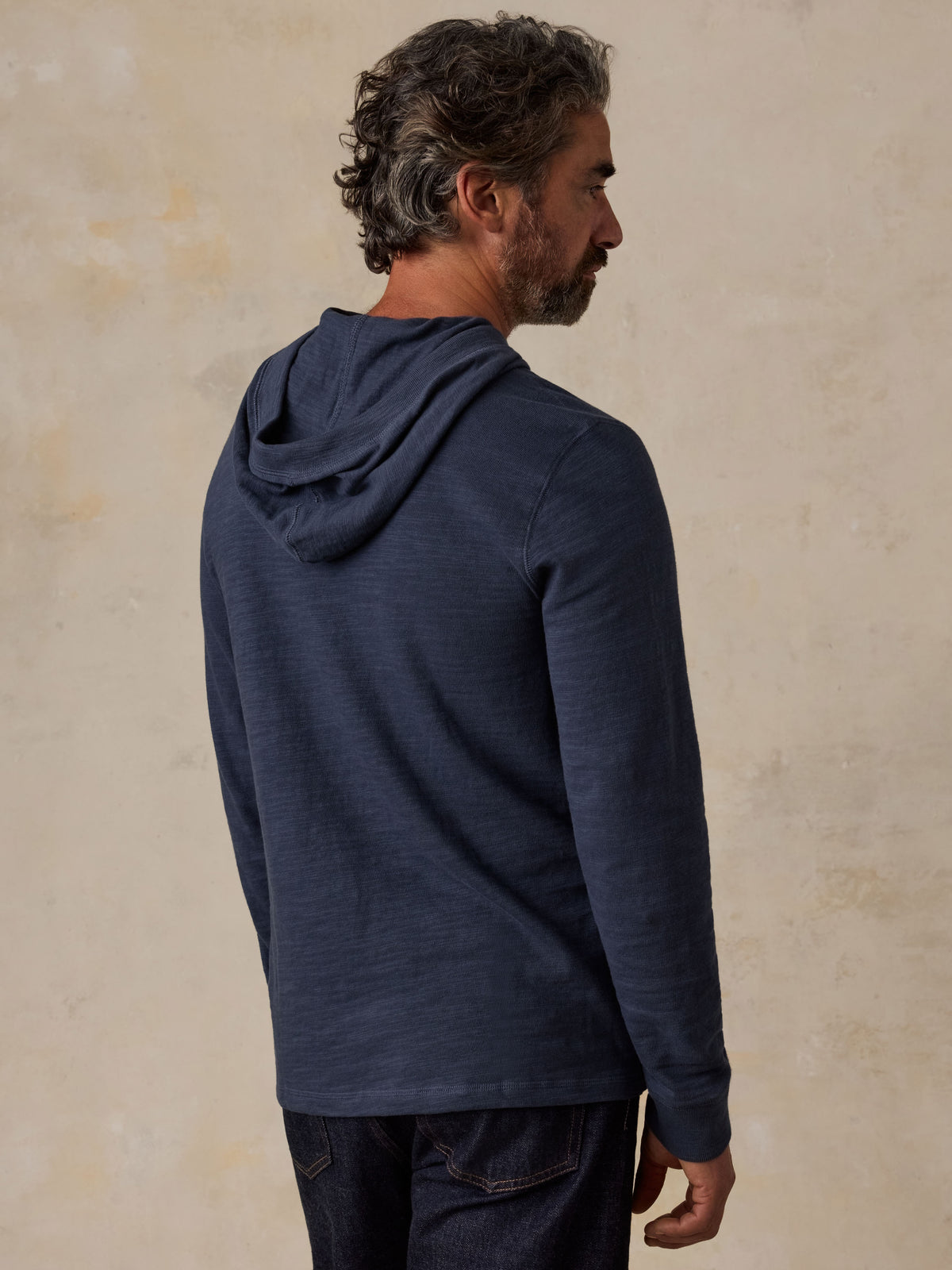 Man viewed from the back wearing a navy NY Giants hoodie and blue jeans, image 5 of 6