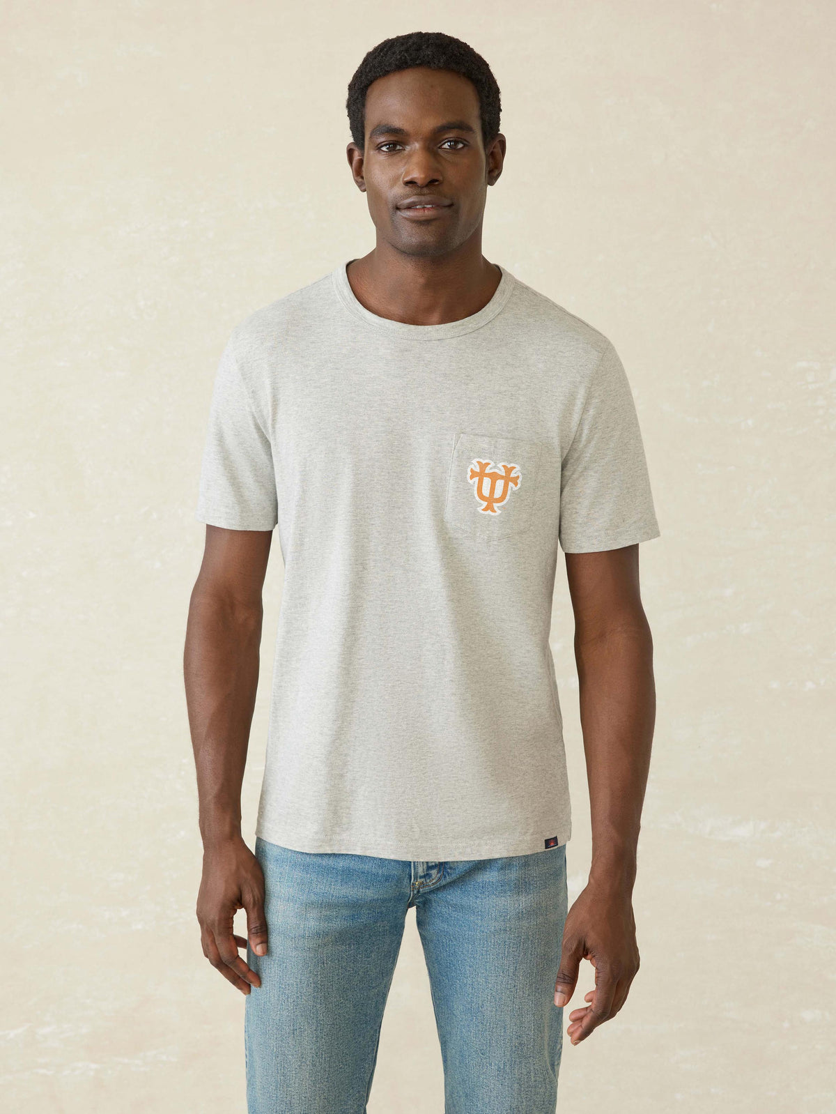 A man wearing a grey University of Tennessee tee and blue jeans, image 1 of 2