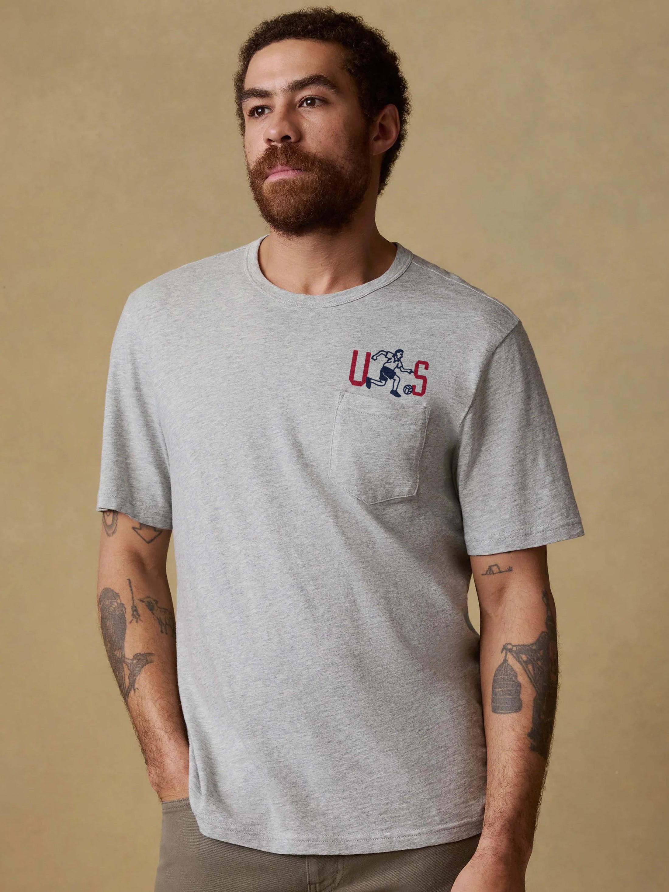 Man wearing a gray t-shirt with a logo against a beige background